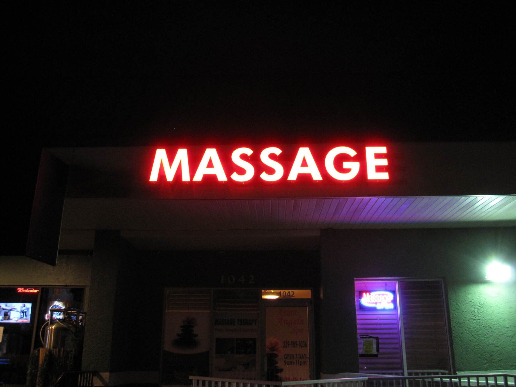 A red sign that says massage is lit up at night
