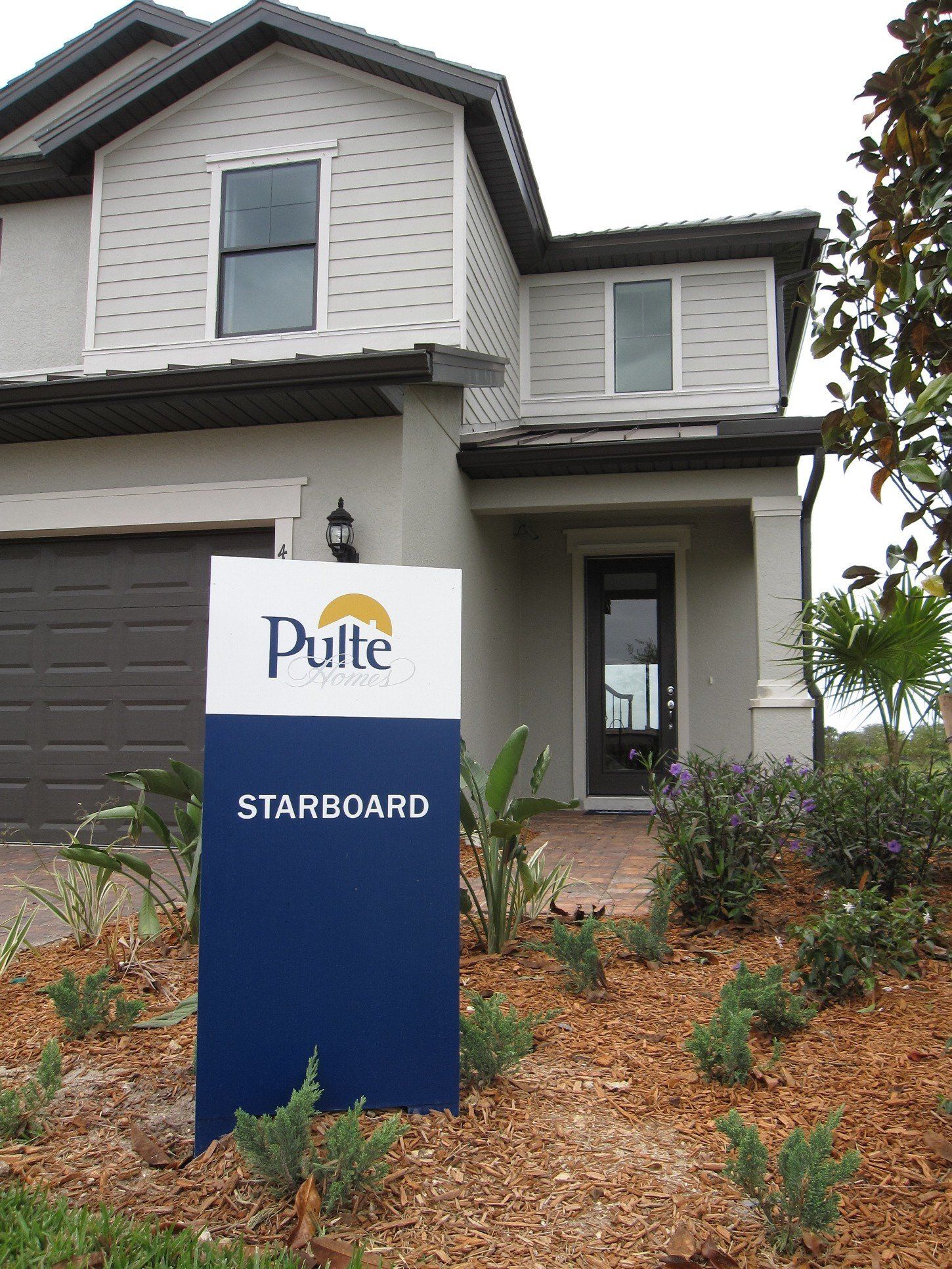 A white house with a blue starboard sign in front of it