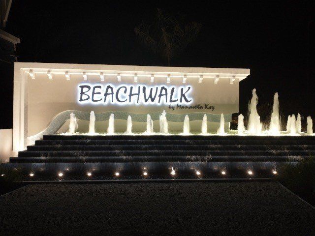 A sign for beachwalk is lit up at night