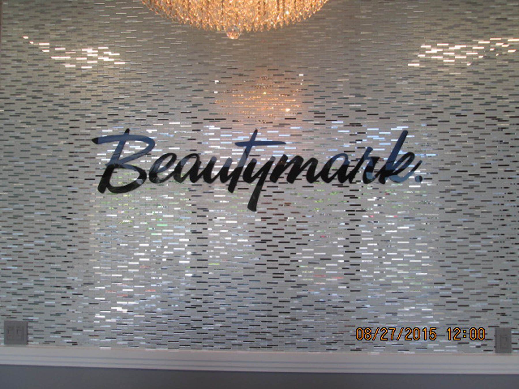 A sign that says beautymark on a wall with a chandelier hanging from the ceiling.