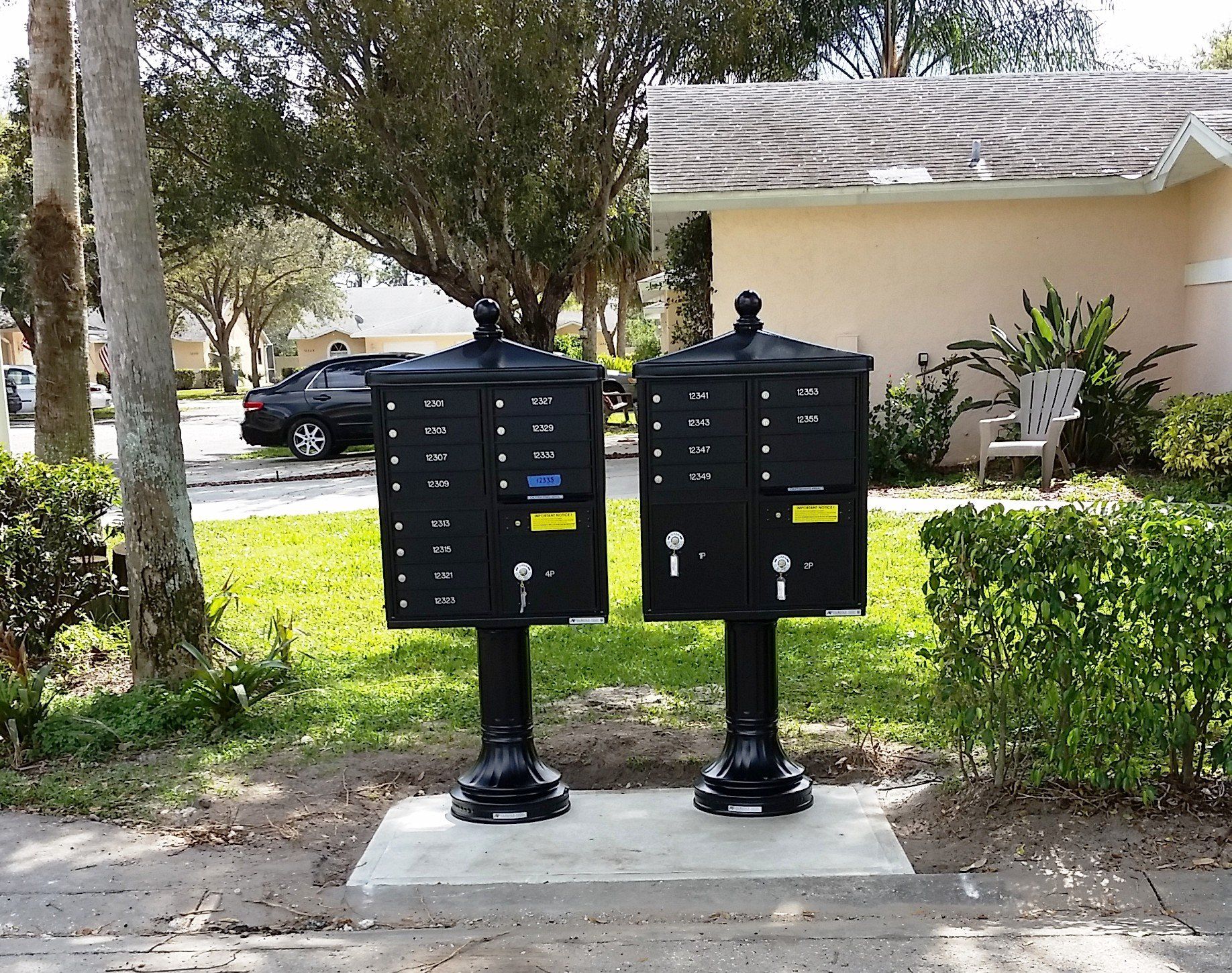 Two black mailboxes are sitting in front of a house