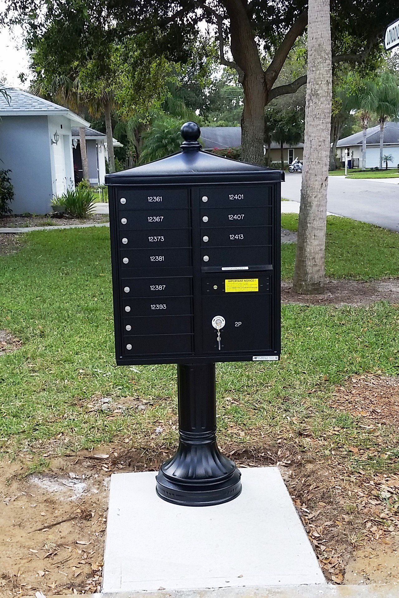 A black mailbox on a post in front of a house