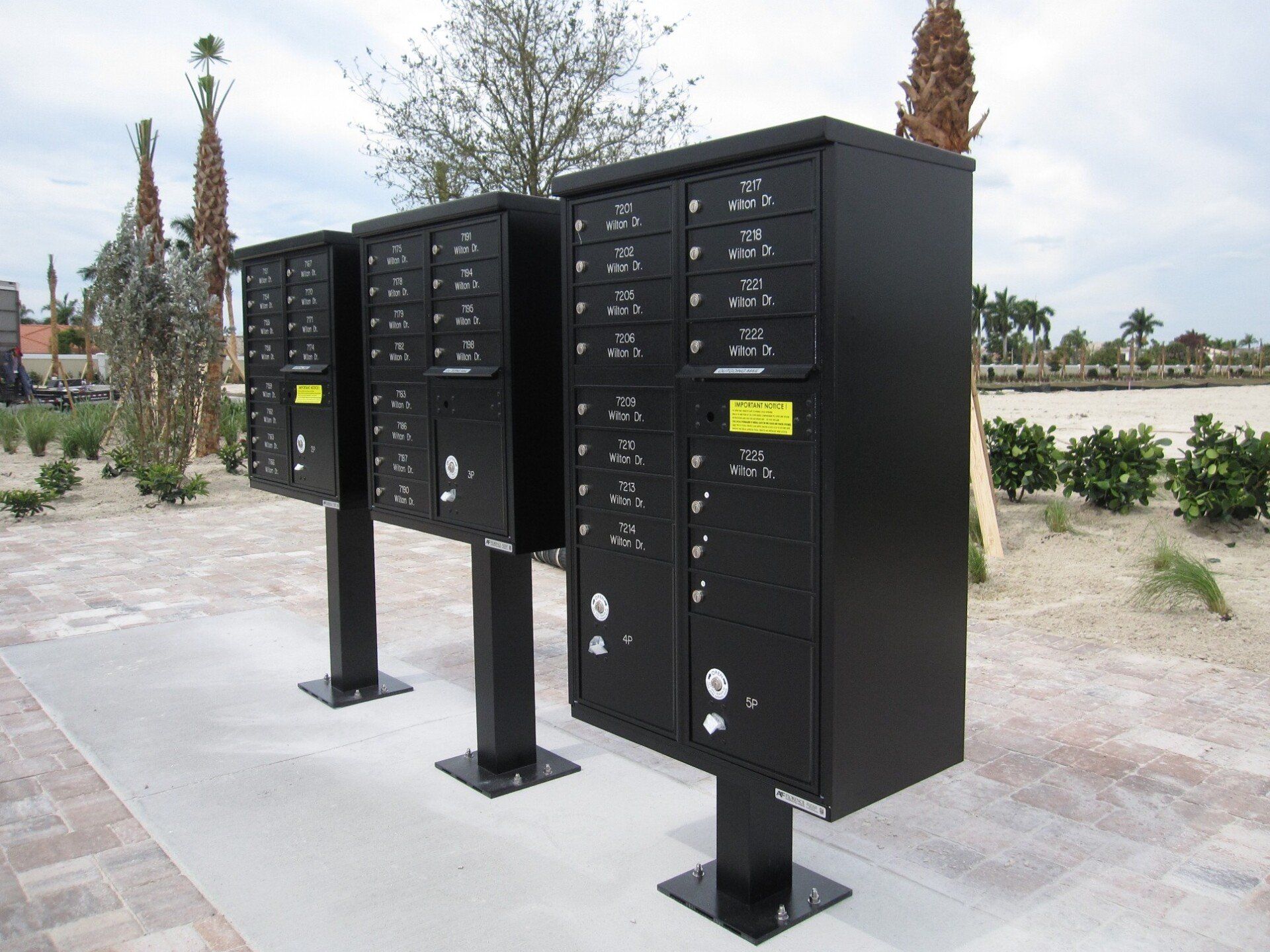 Three black mailboxes are lined up on a sidewalk