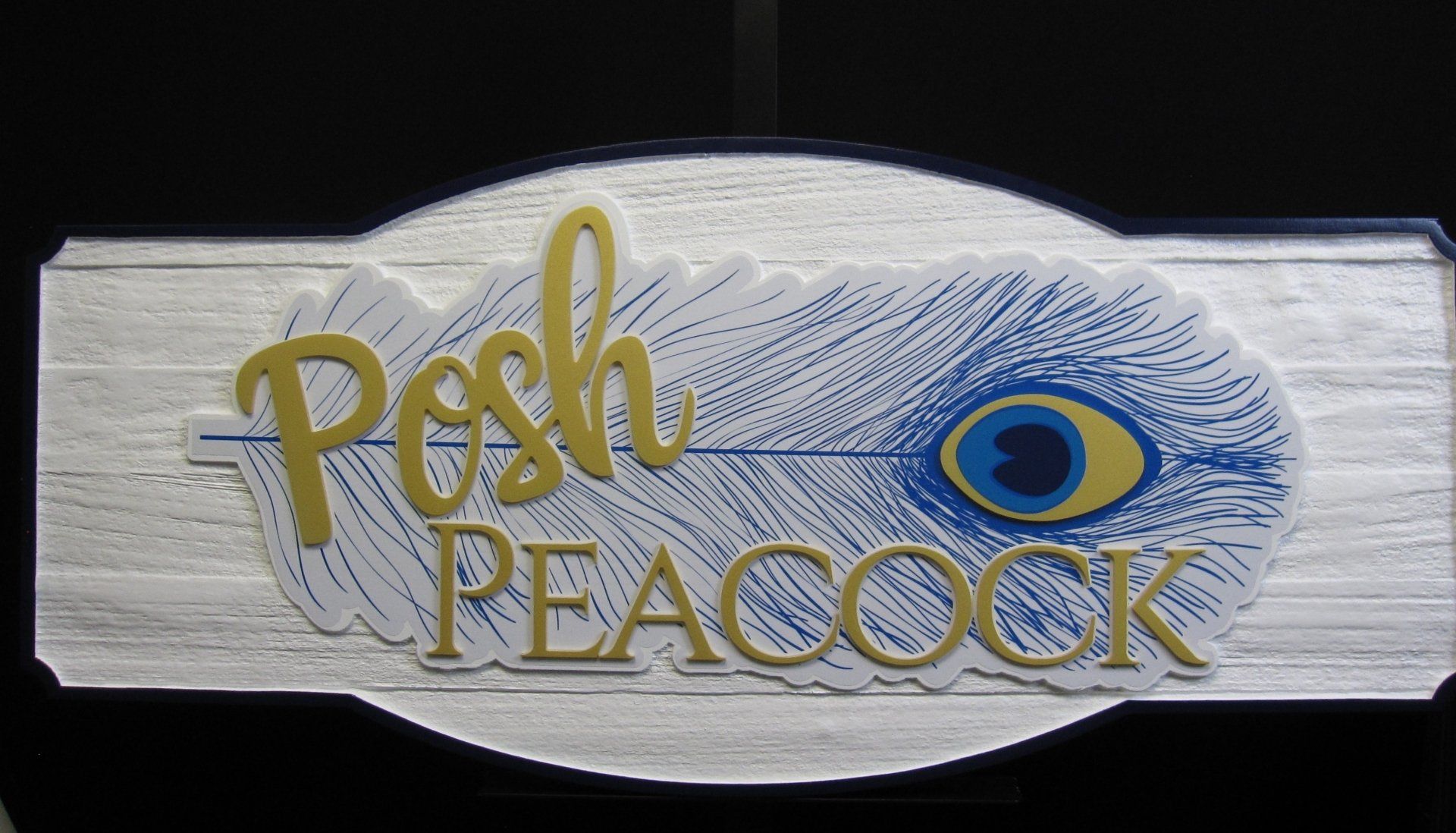 A sign that says posh peacock with a peacock feather on it