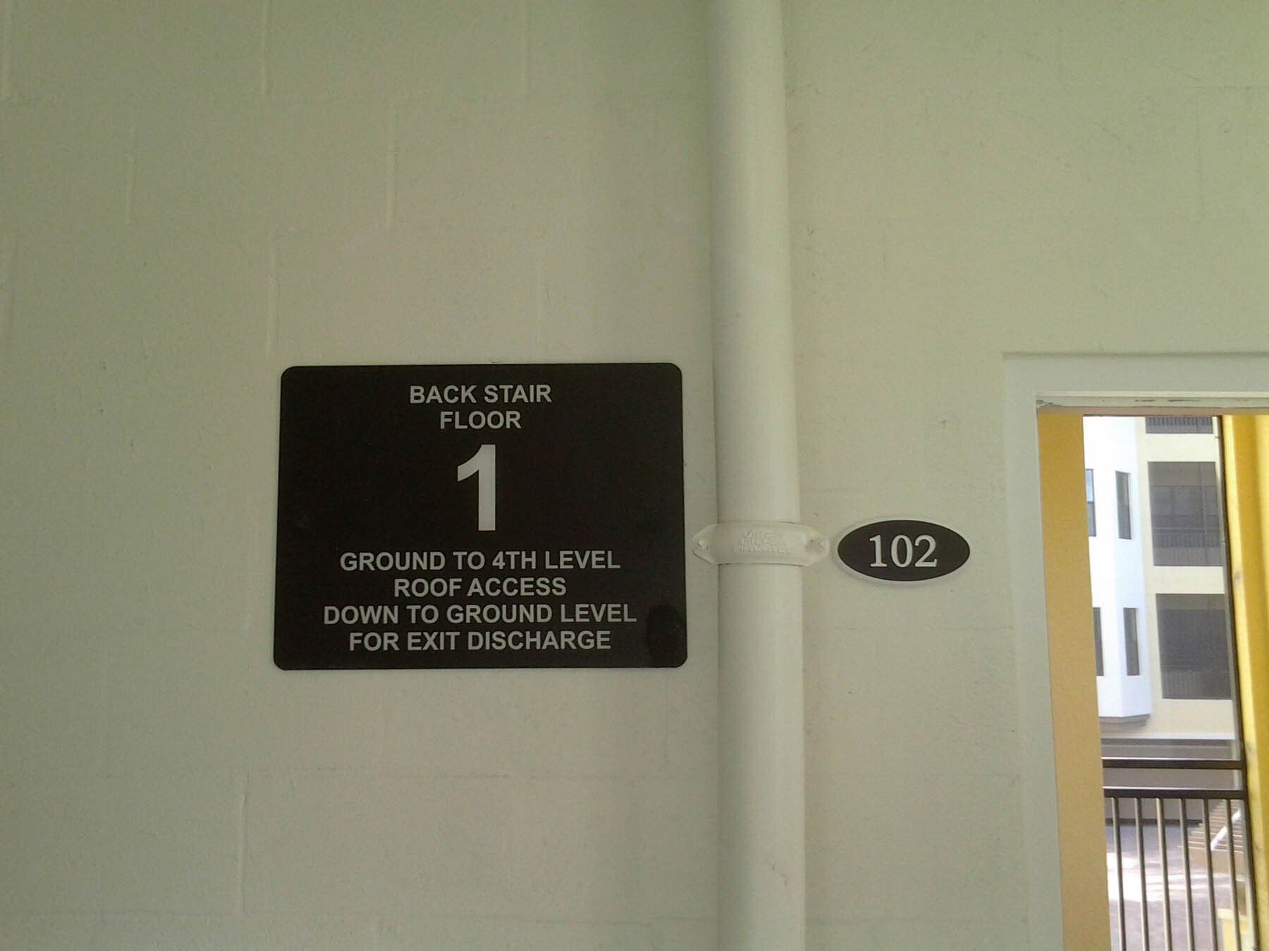 A sign on a wall that says back stair floor 1