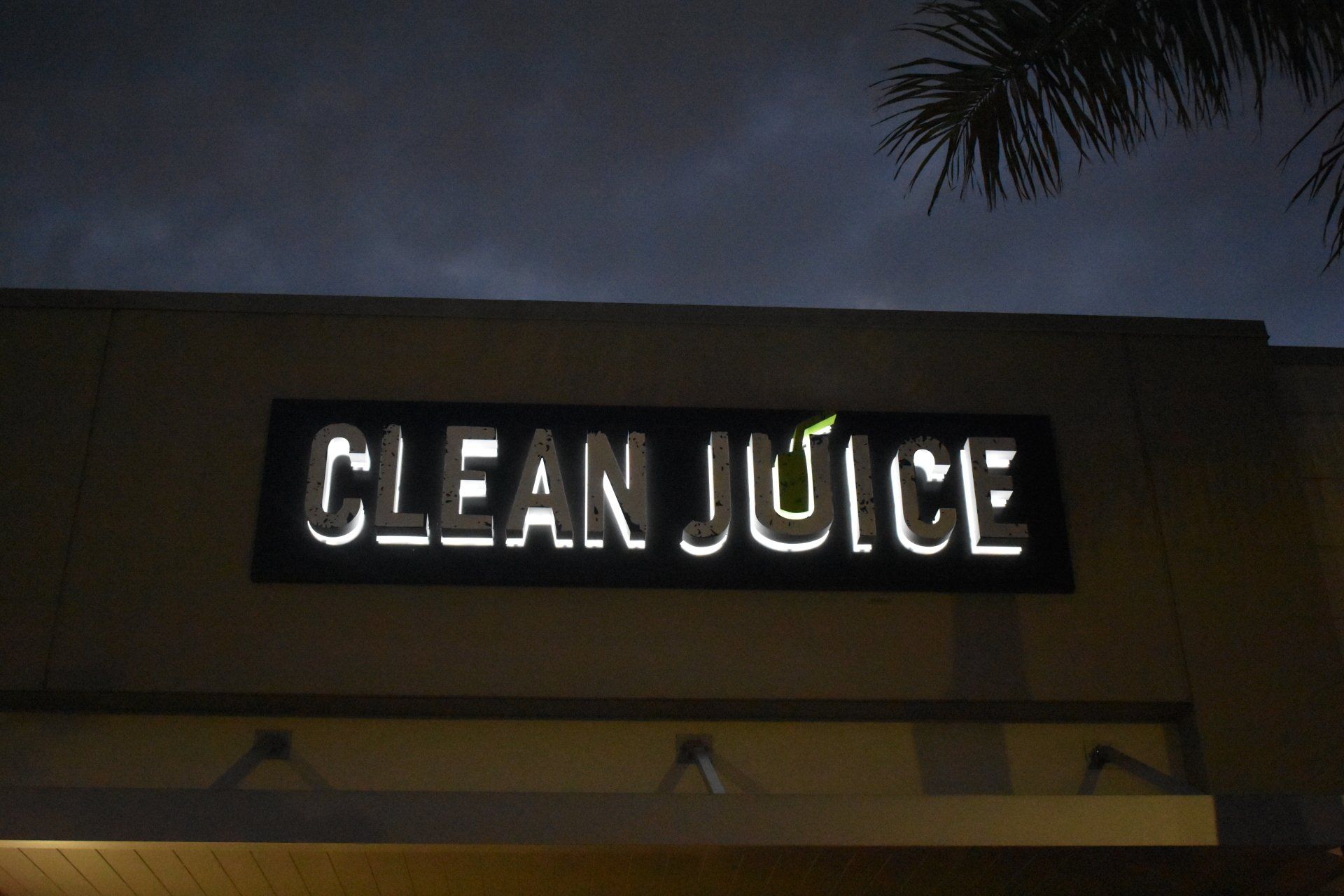 A clean juice sign is lit up at night