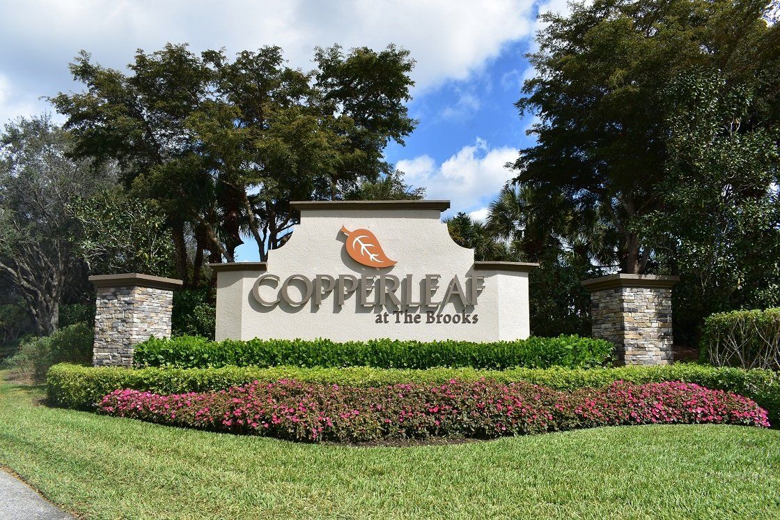 A sign for copperleaf is surrounded by flowers and trees