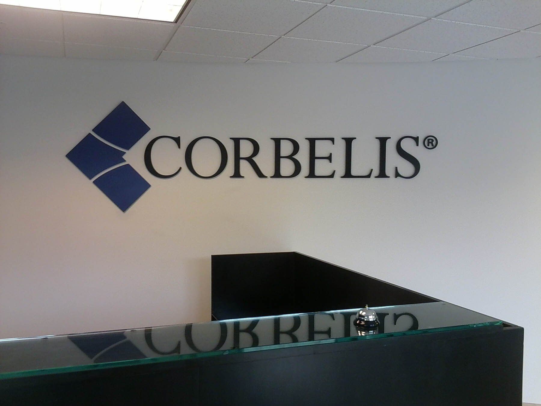 Corbelis logo on a white wall above a glass counter