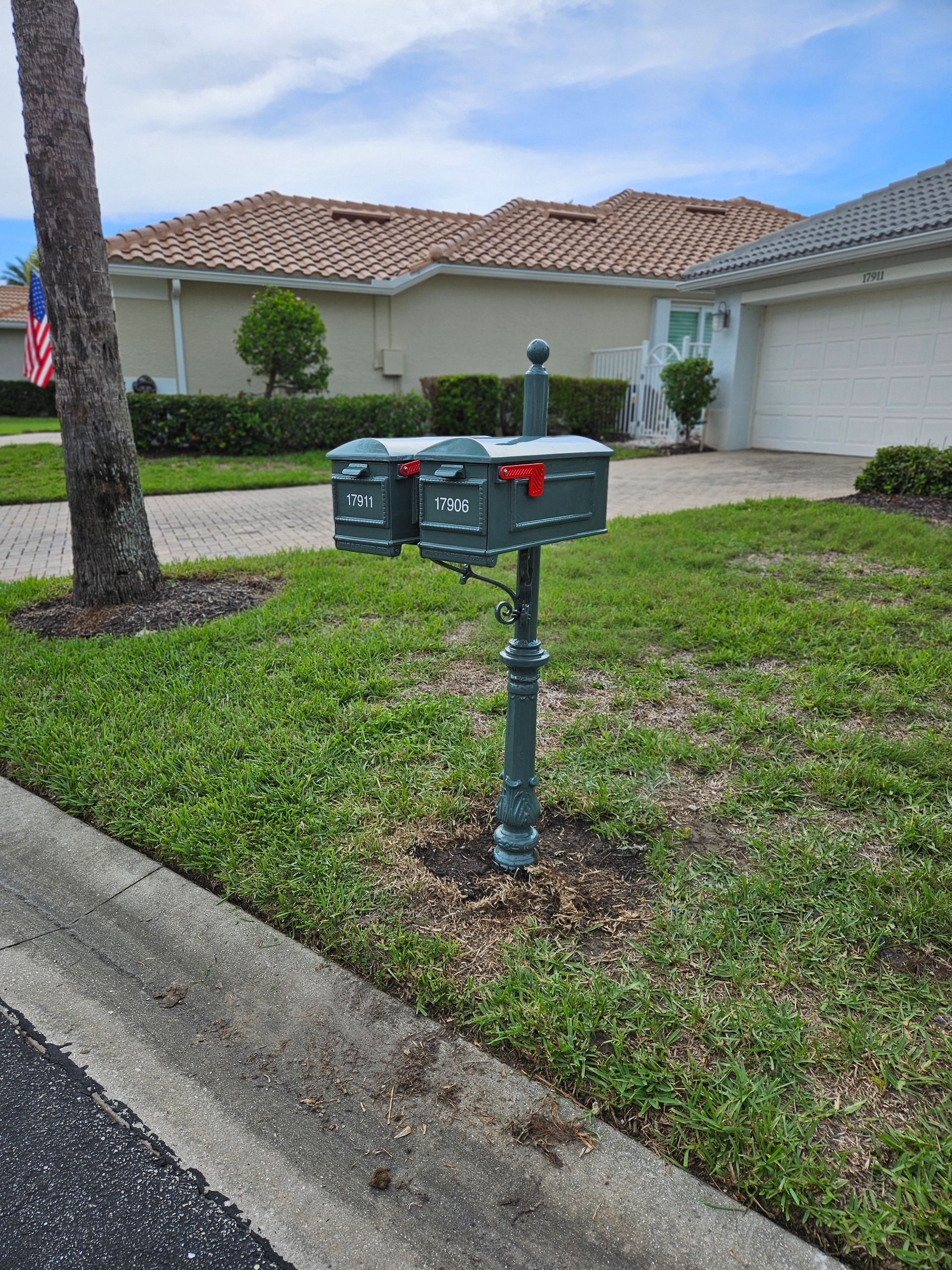 A mailbox is sitting on the side of the road in front of a house.