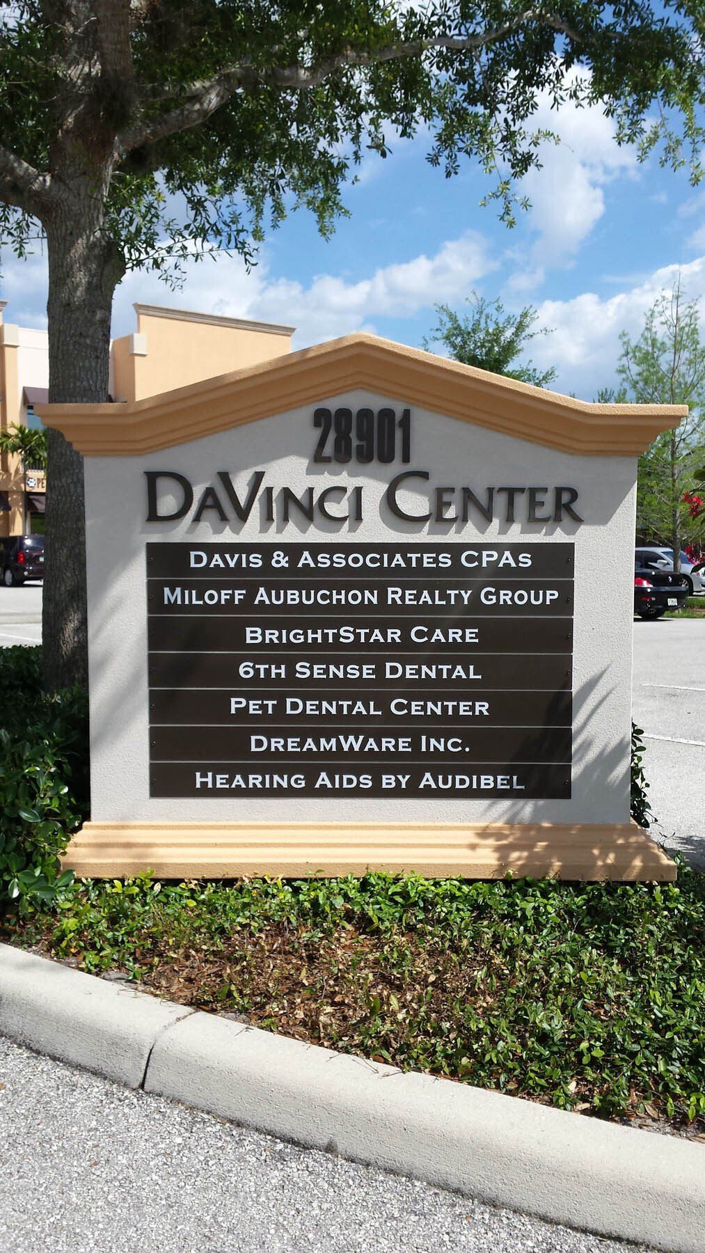 A sign for davinci center is sitting in front of a tree.