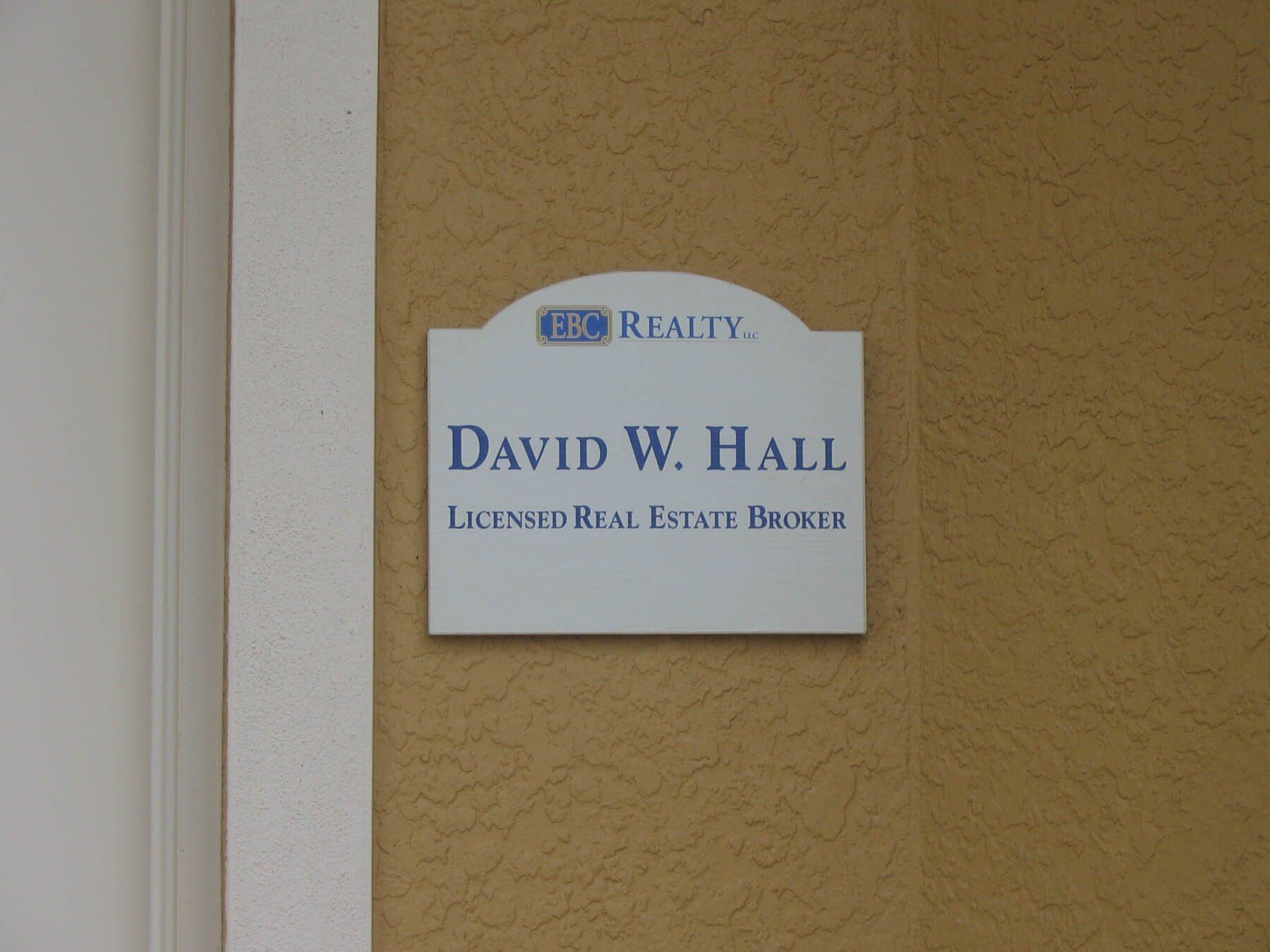 A sign on a wall that says david w hall licensed real estate broker