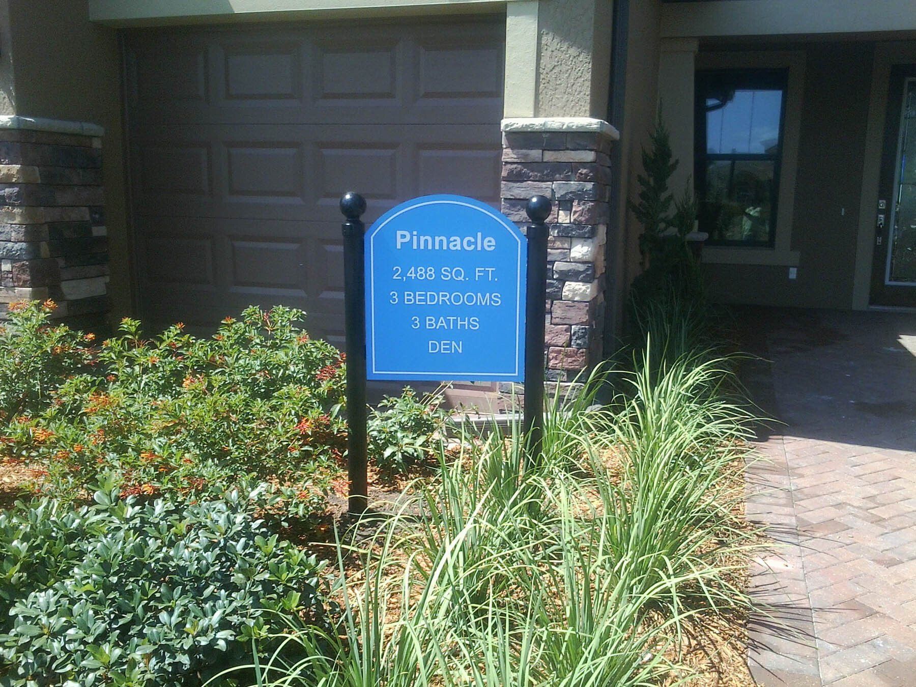 A blue sign in front of a house says pinnacle