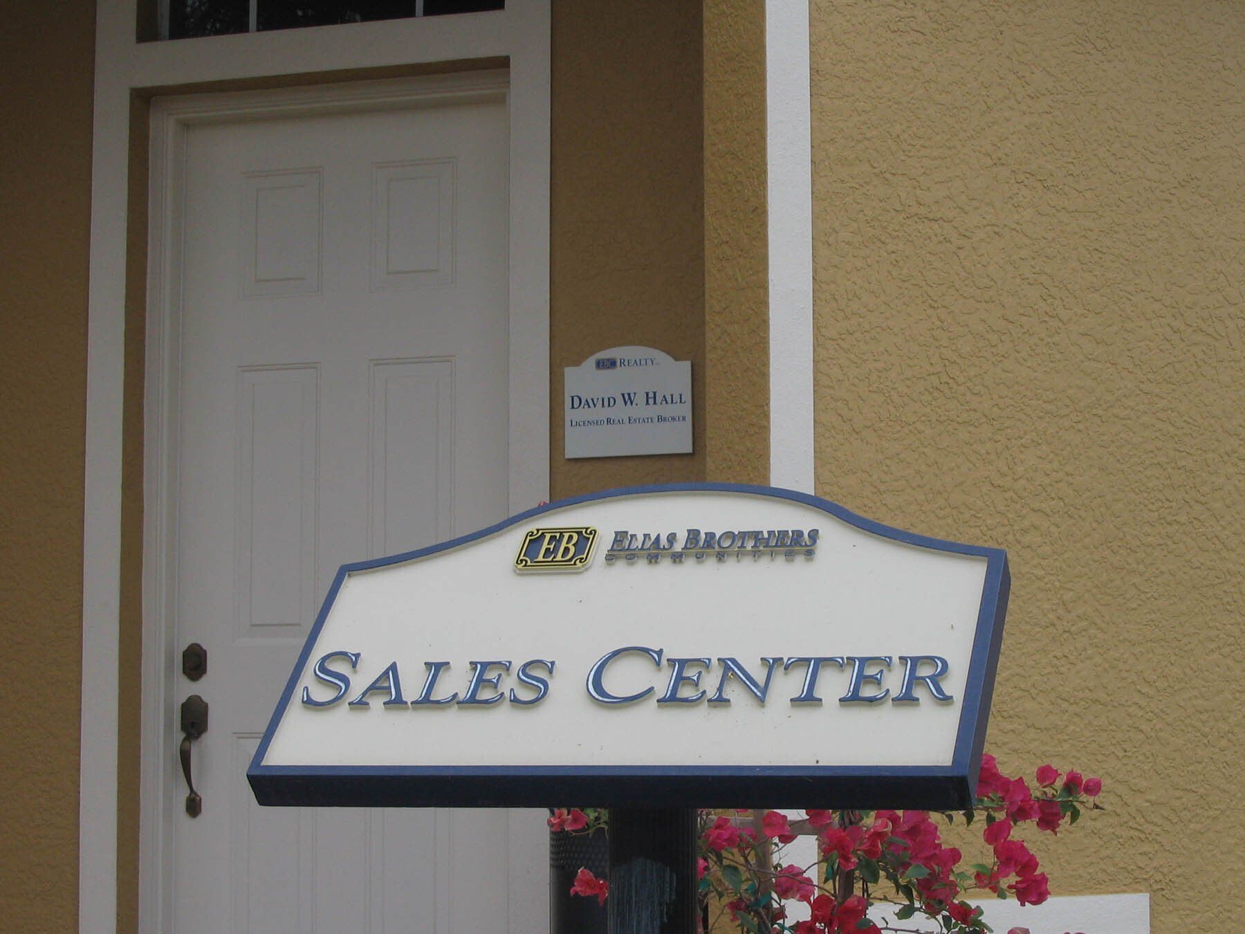 A sales center sign in front of a door