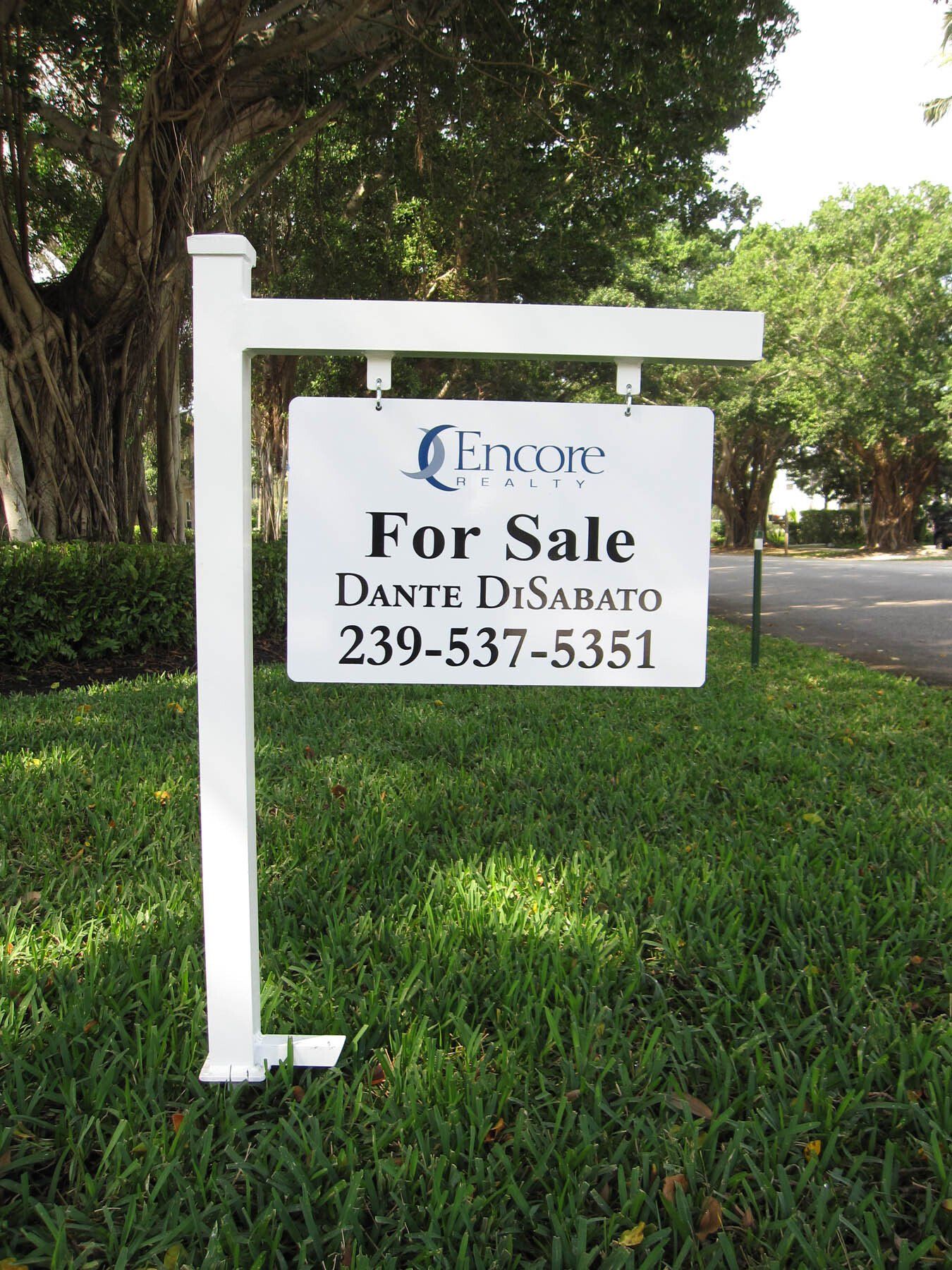 A white for sale sign is sitting in the grass