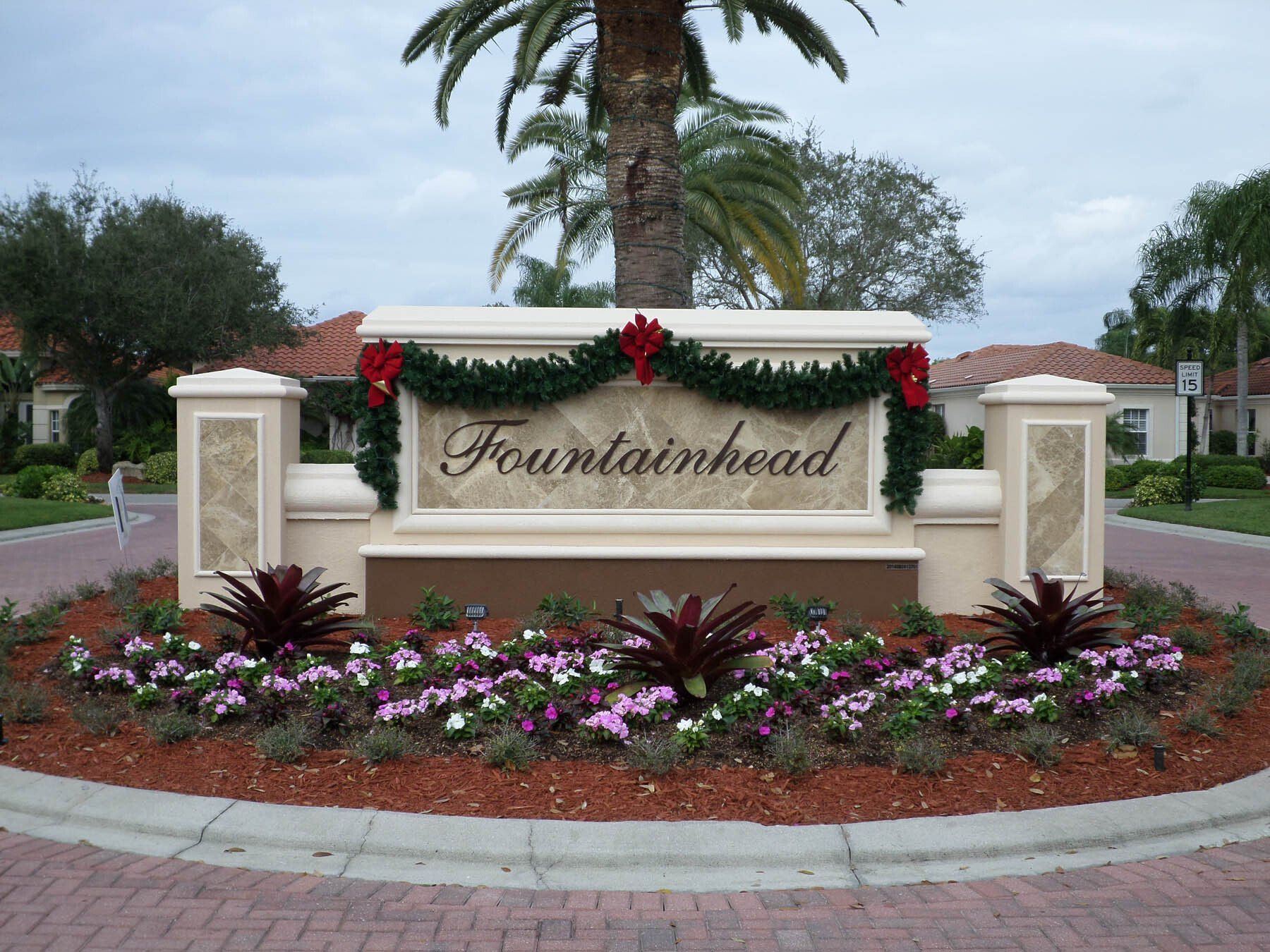 A sign for fountainhead is surrounded by flowers and palm trees