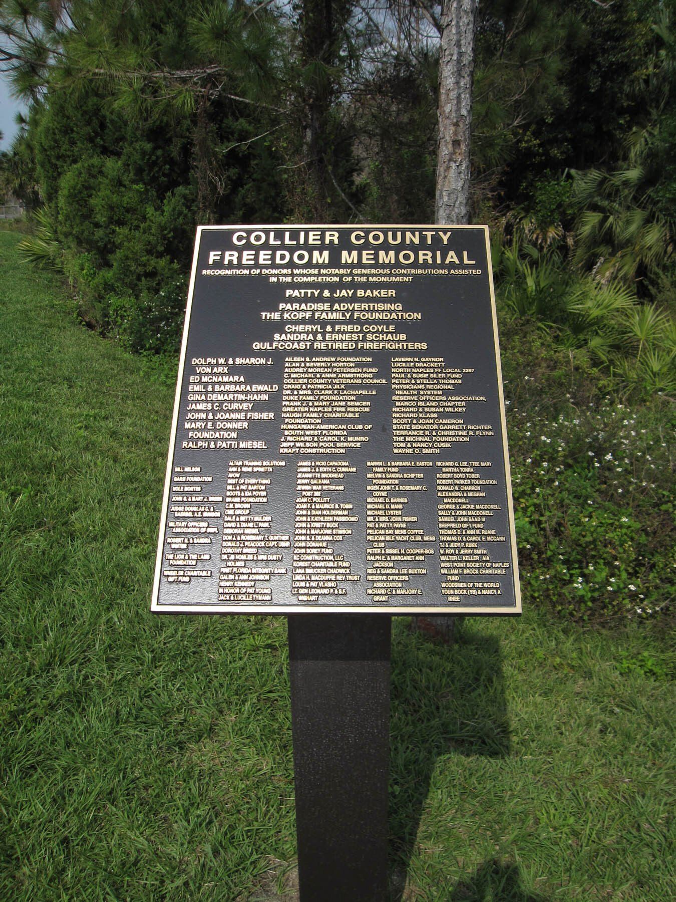 A plaque on a pole that says collier county freedom memorial