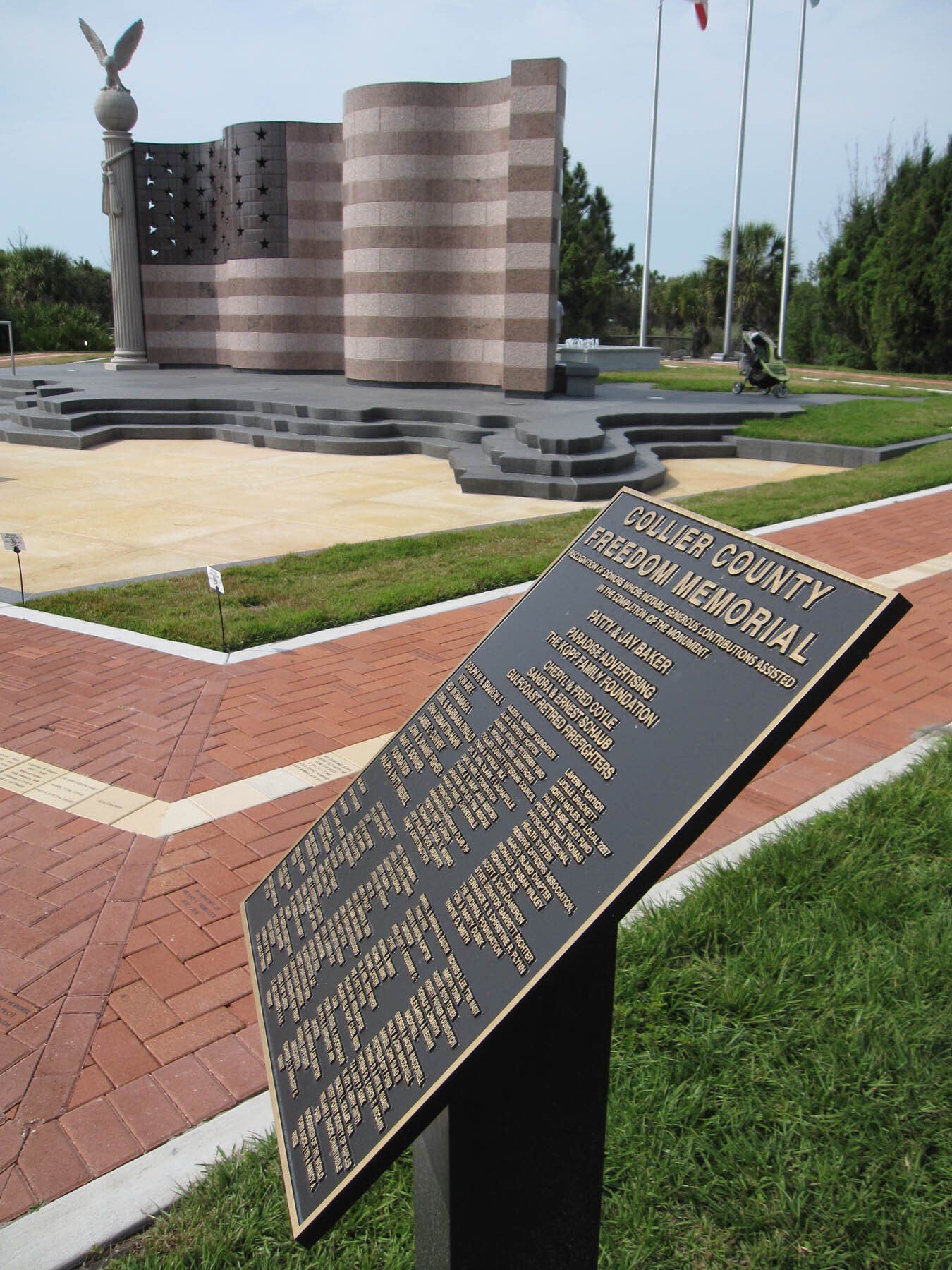 A plaque in front of a large american flag memorial