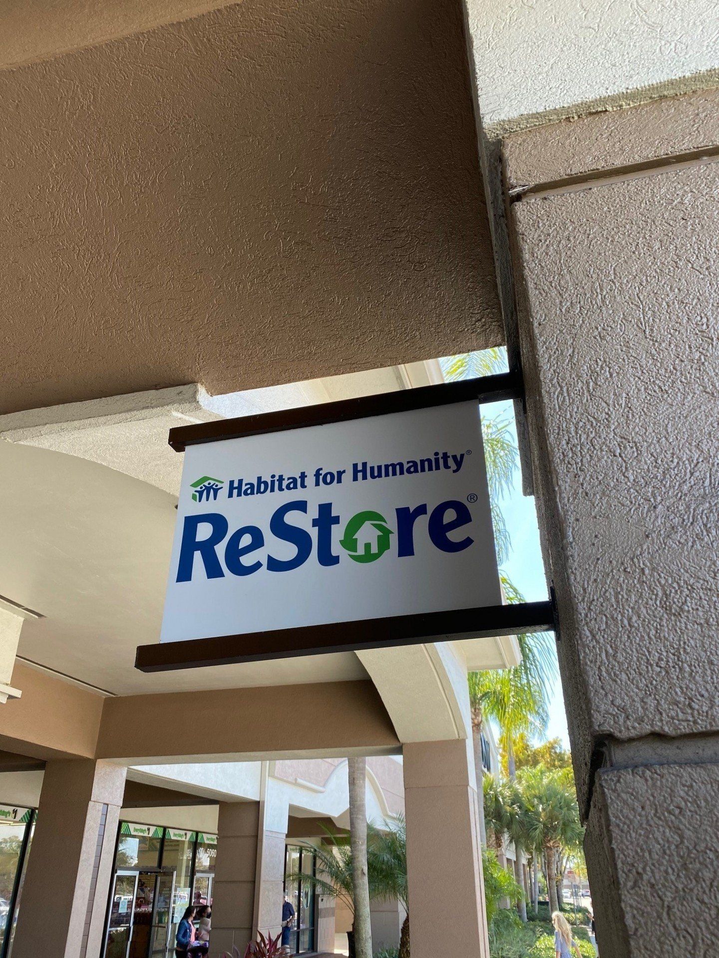 A sign for the habitat for humanity restore hangs from the side of a building.