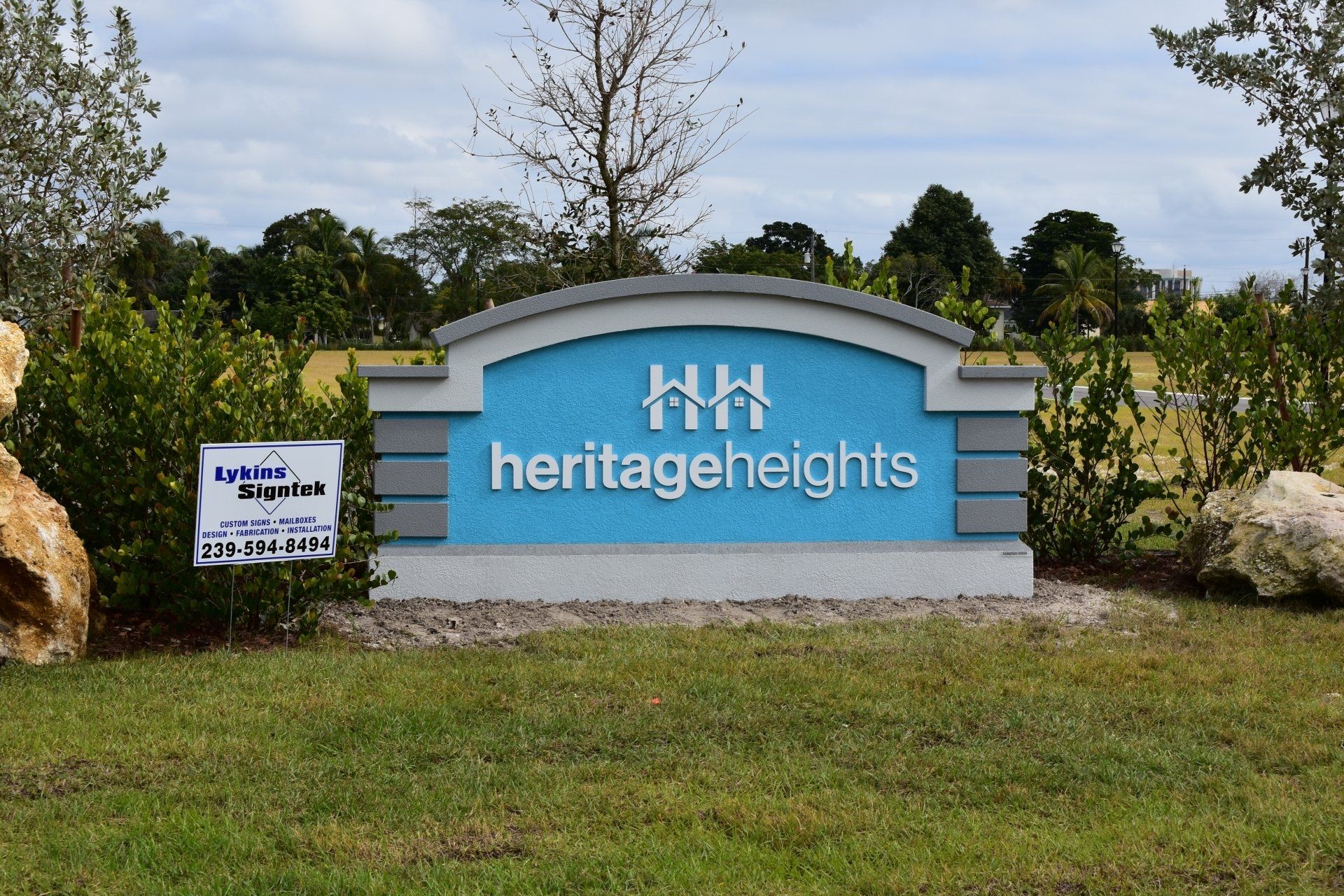 A sign for heritage heights is in the middle of a grassy field
