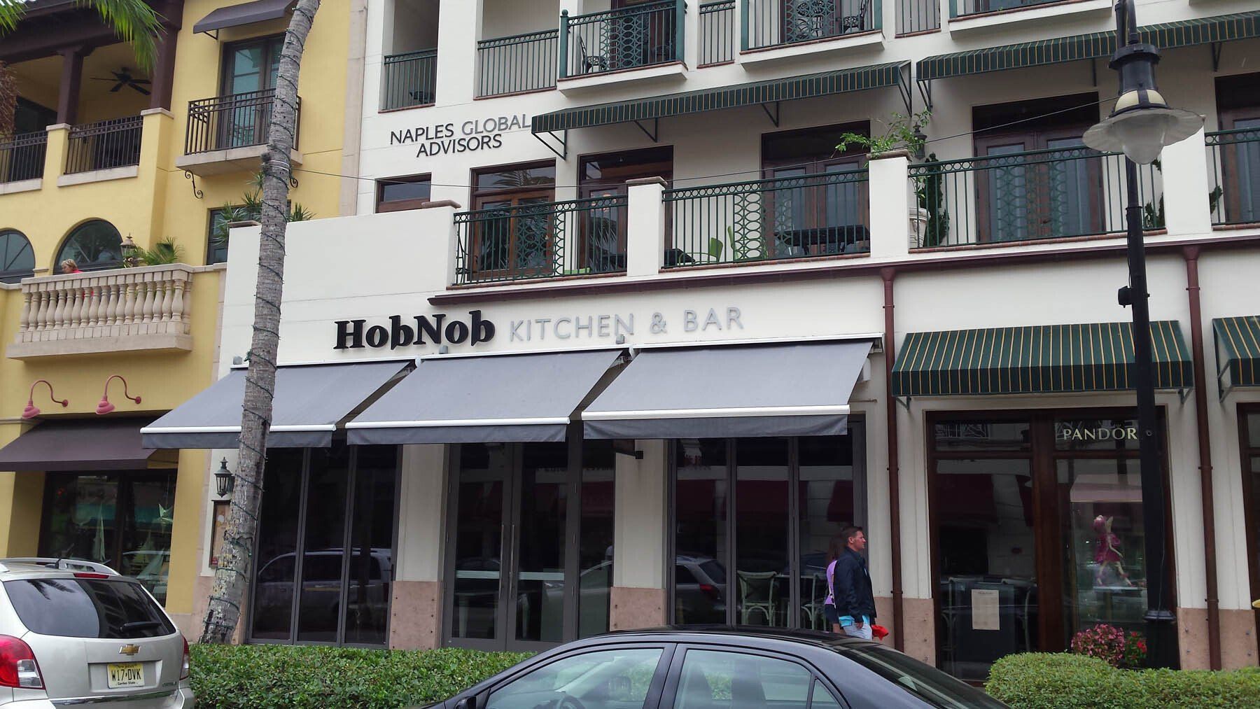 A car is parked in front of a restaurant called hohnob kitchen & bar