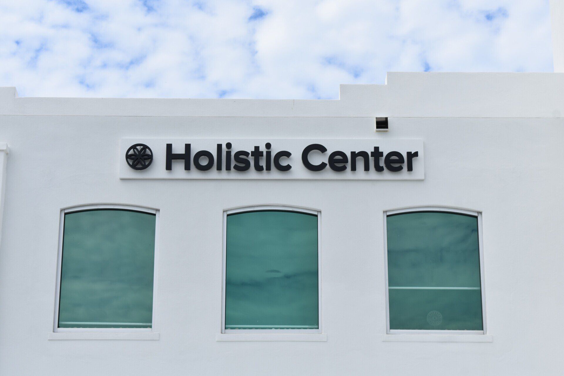 A white building with a sign that says holistic center on it.