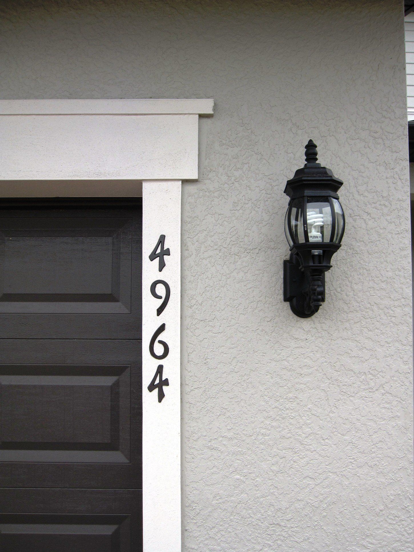 A black garage door with the number 4964 on it