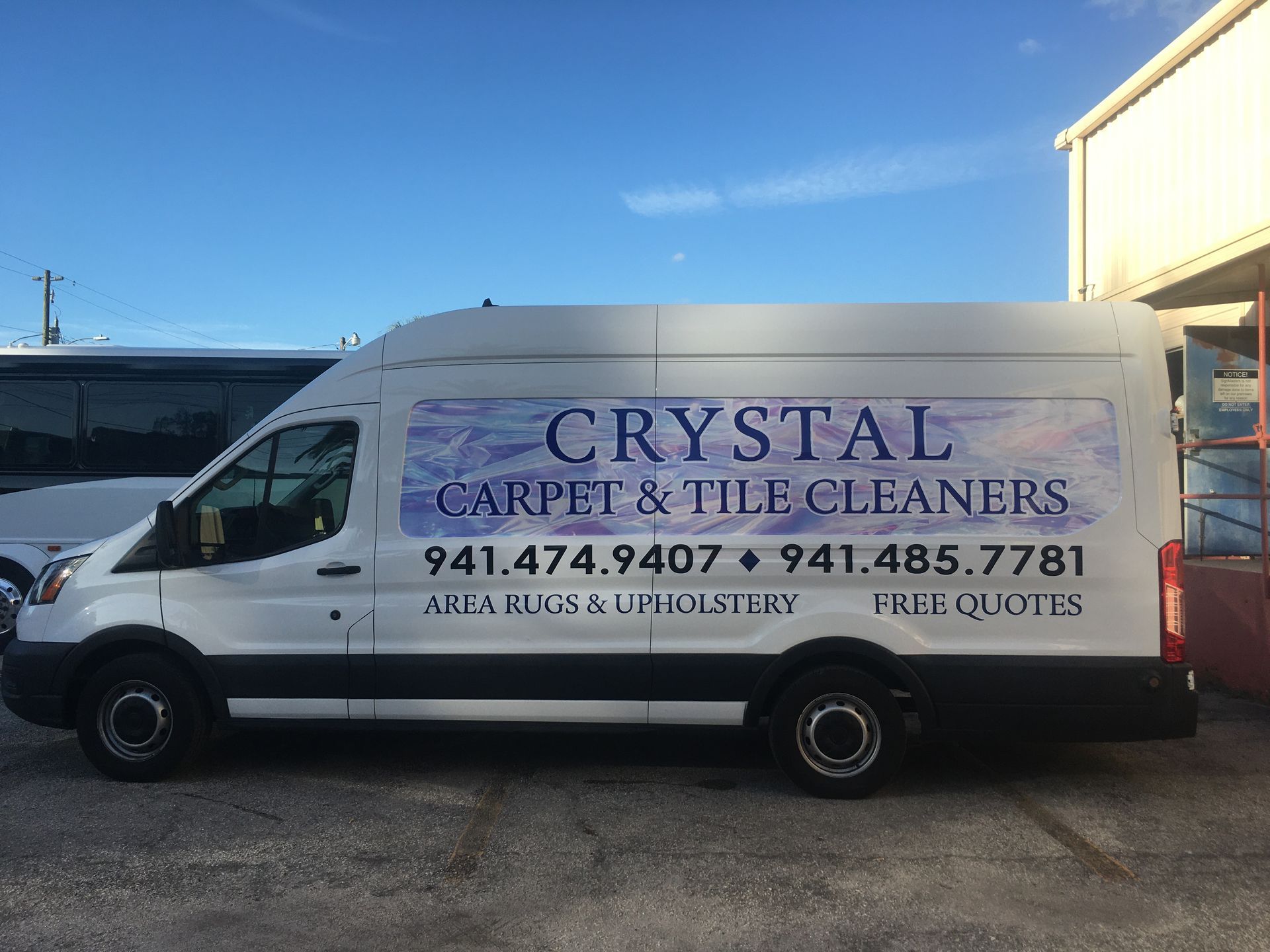 A white van for crystal carpet and tile cleaners is parked in front of a building.