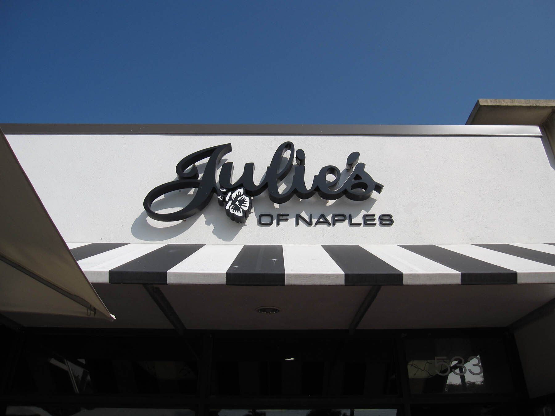 A sign for julie 's of naples with a black and white awning
