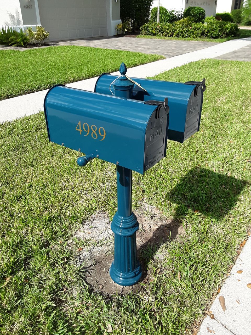 A blue mailbox with the number 4096 on it is in the grass.