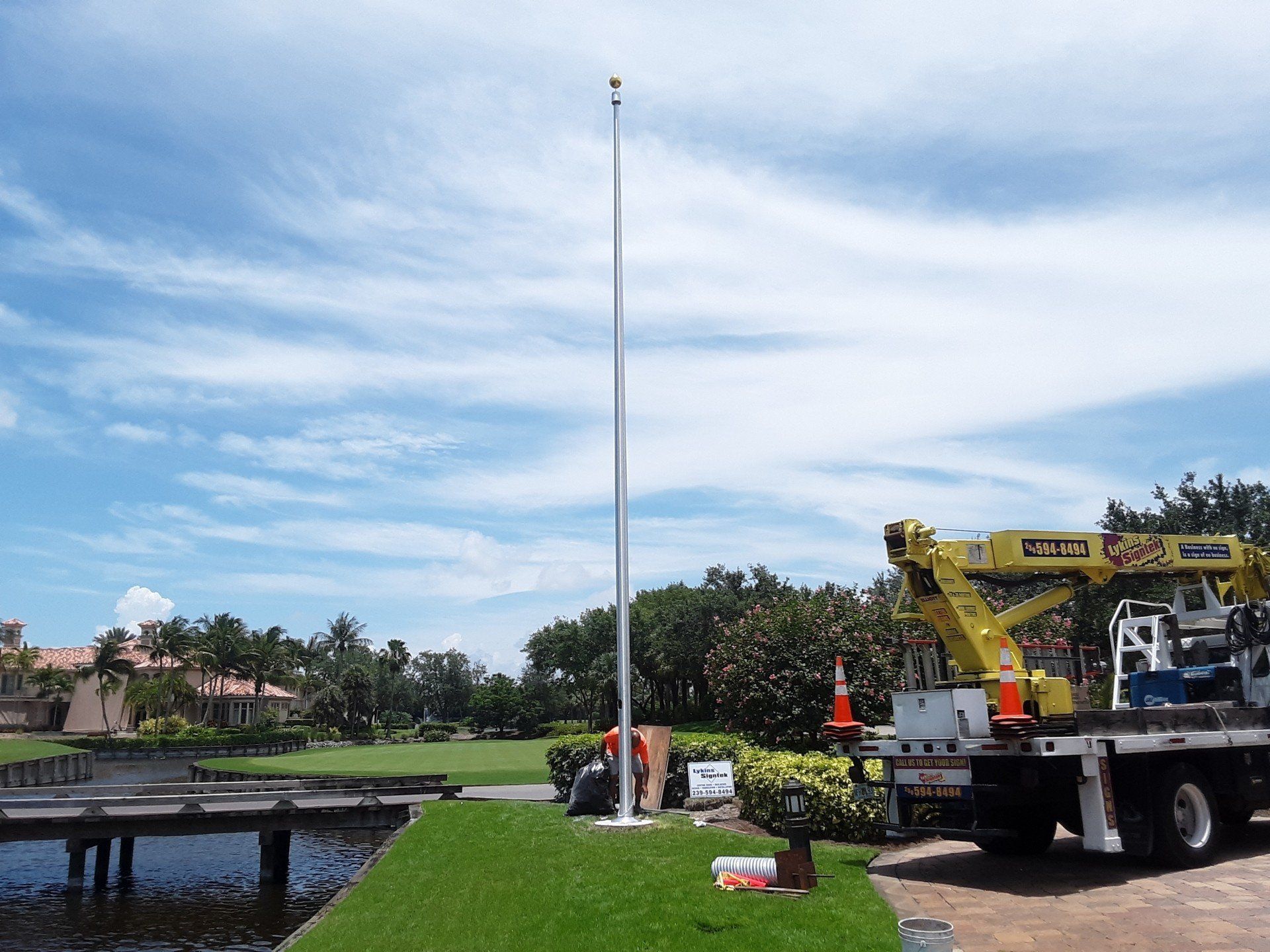 A yellow crane is sitting next to a flag pole
