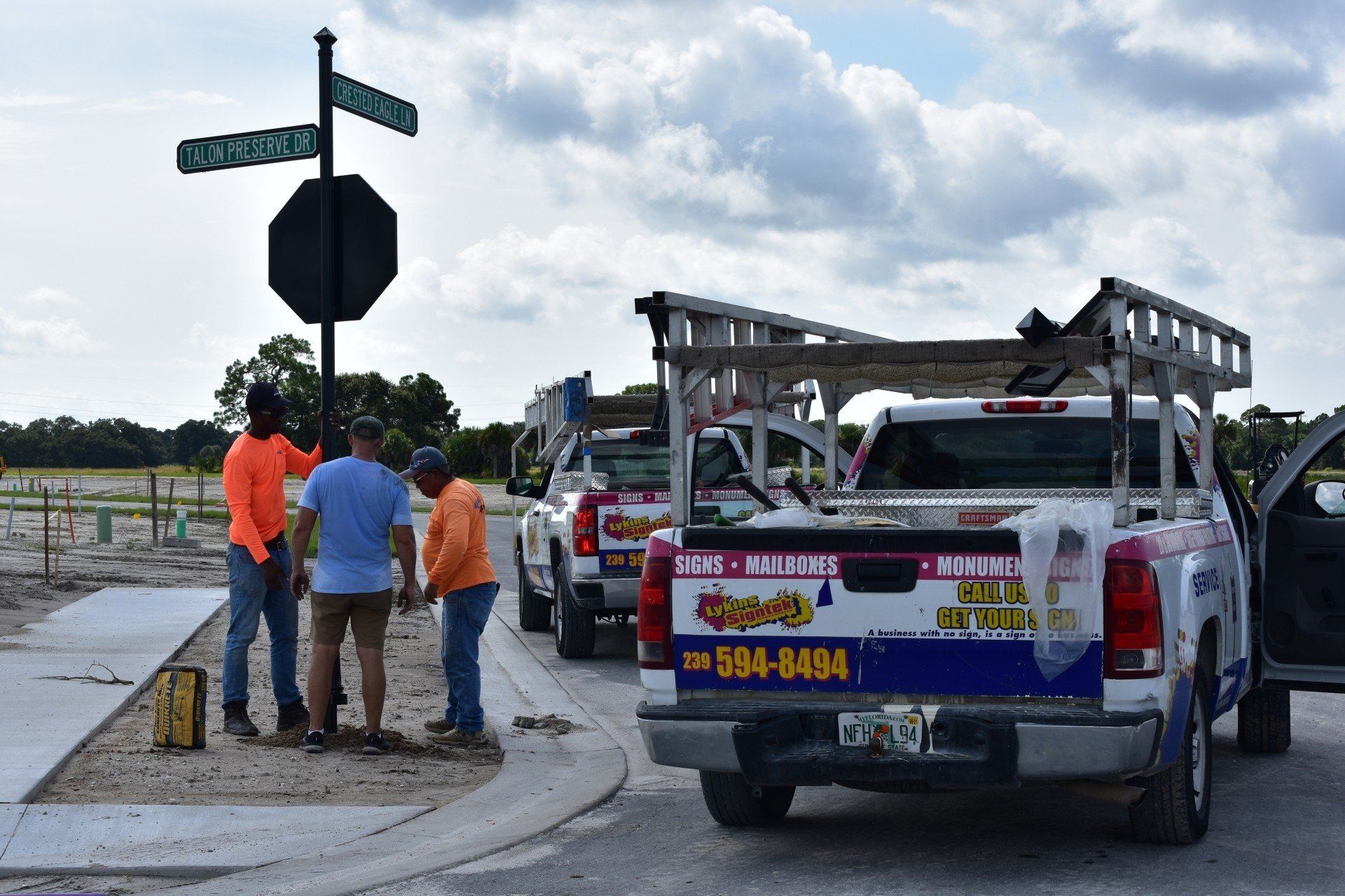 A group of construction workers are standing around a row of trucks.