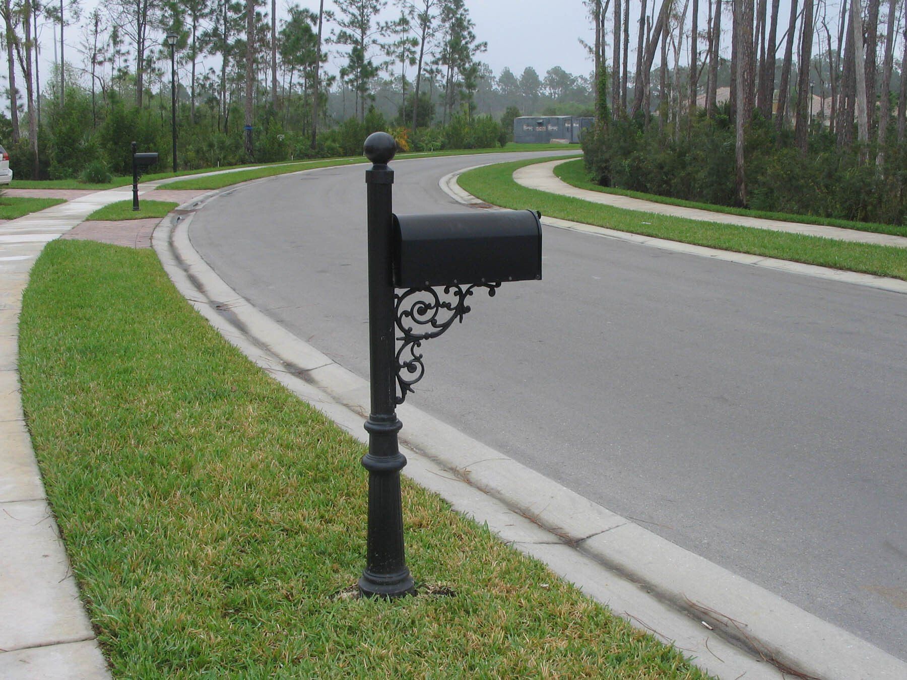 A black mailbox on the side of a road