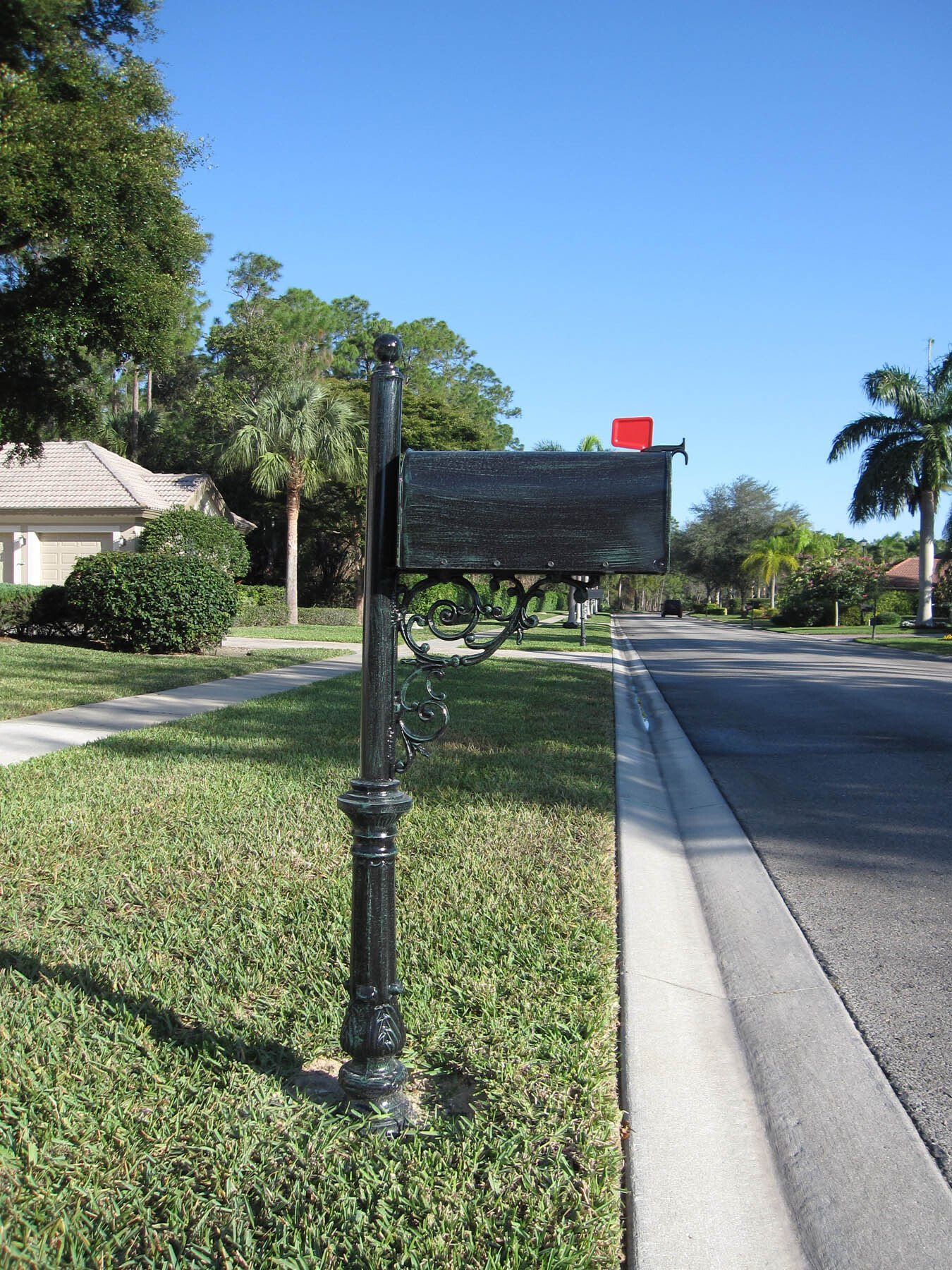 A black mailbox is on the side of the road