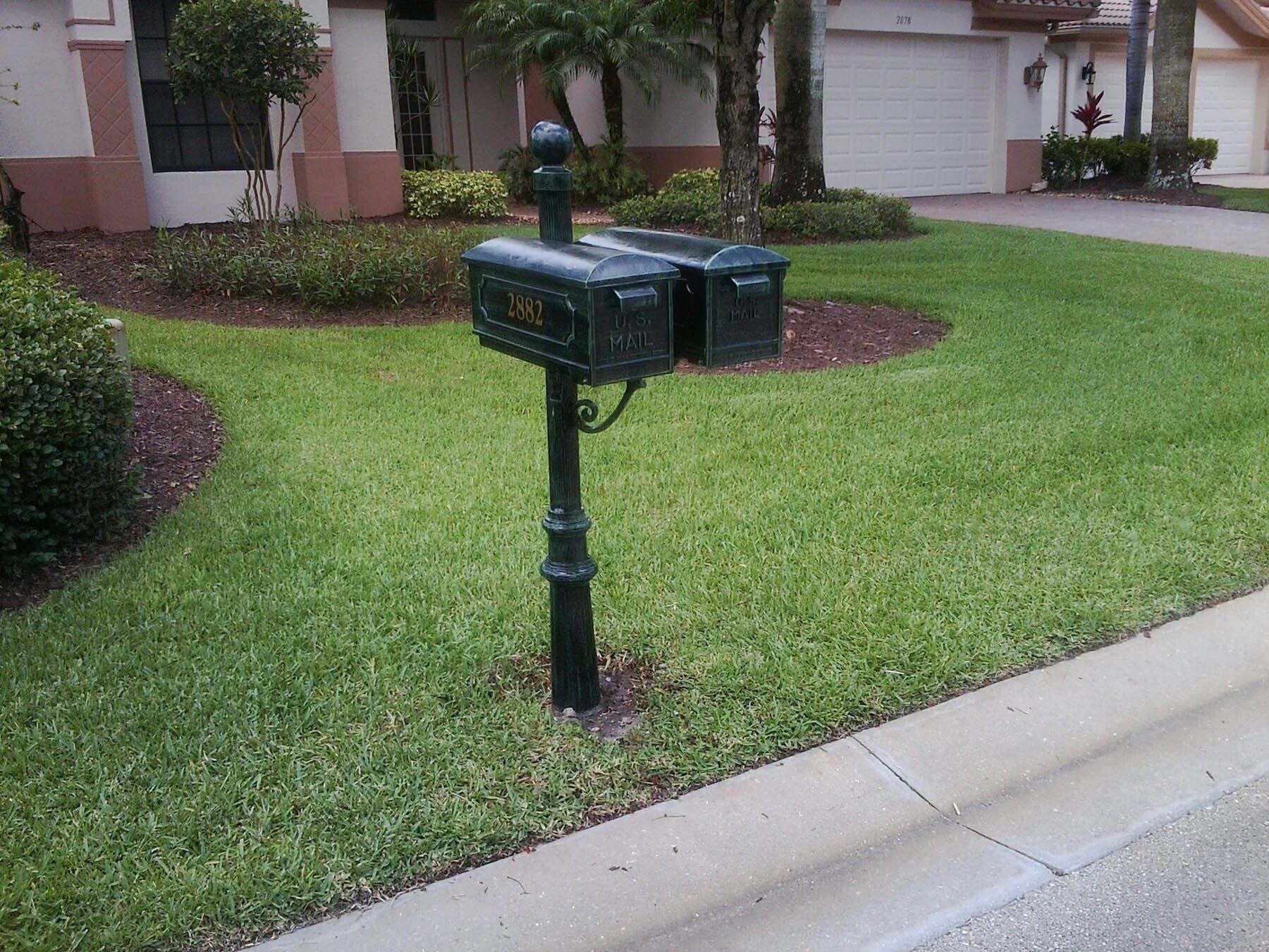 A black mailbox is in the middle of a lush green lawn