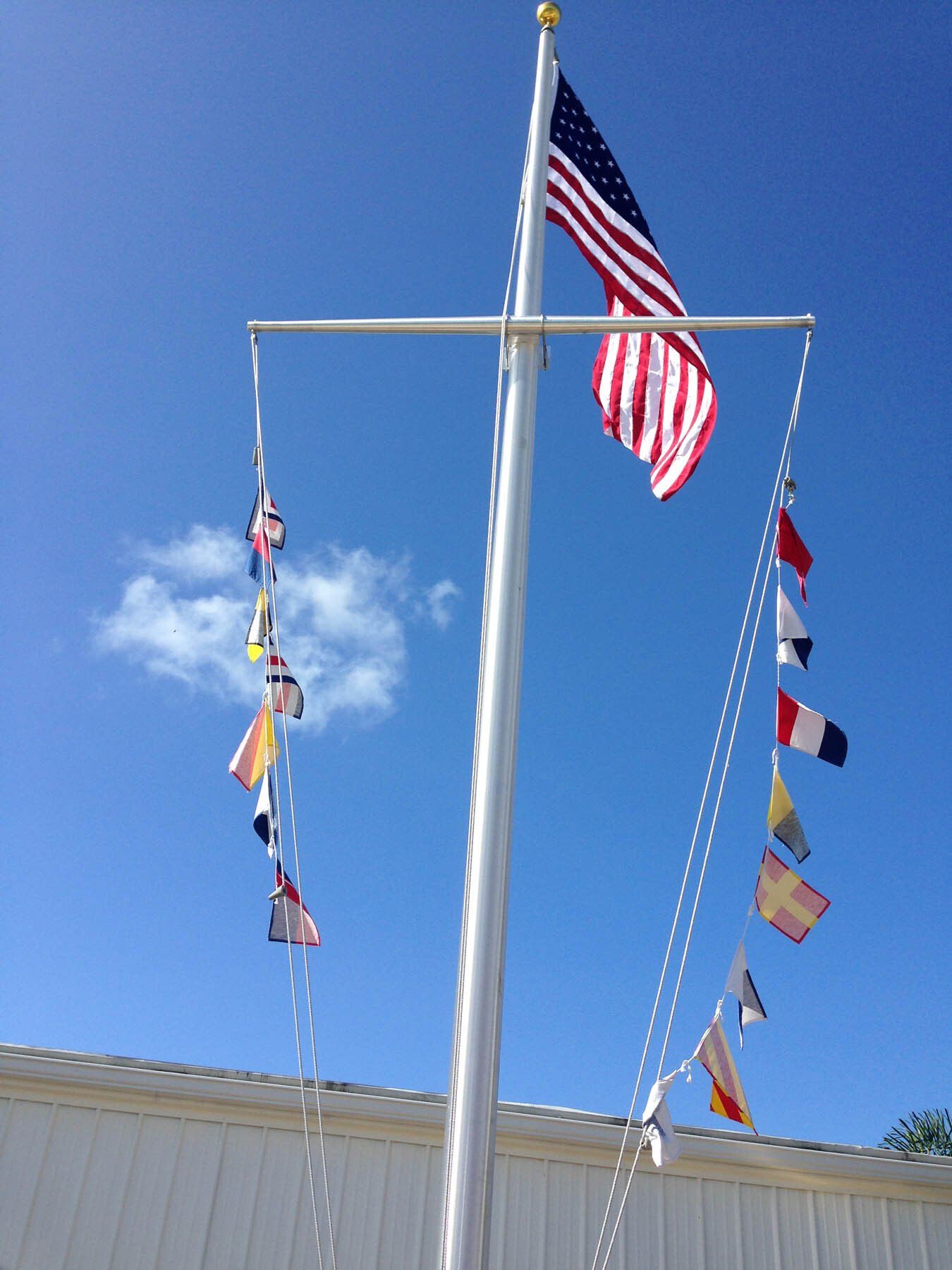 A flag pole with many flags hanging from it