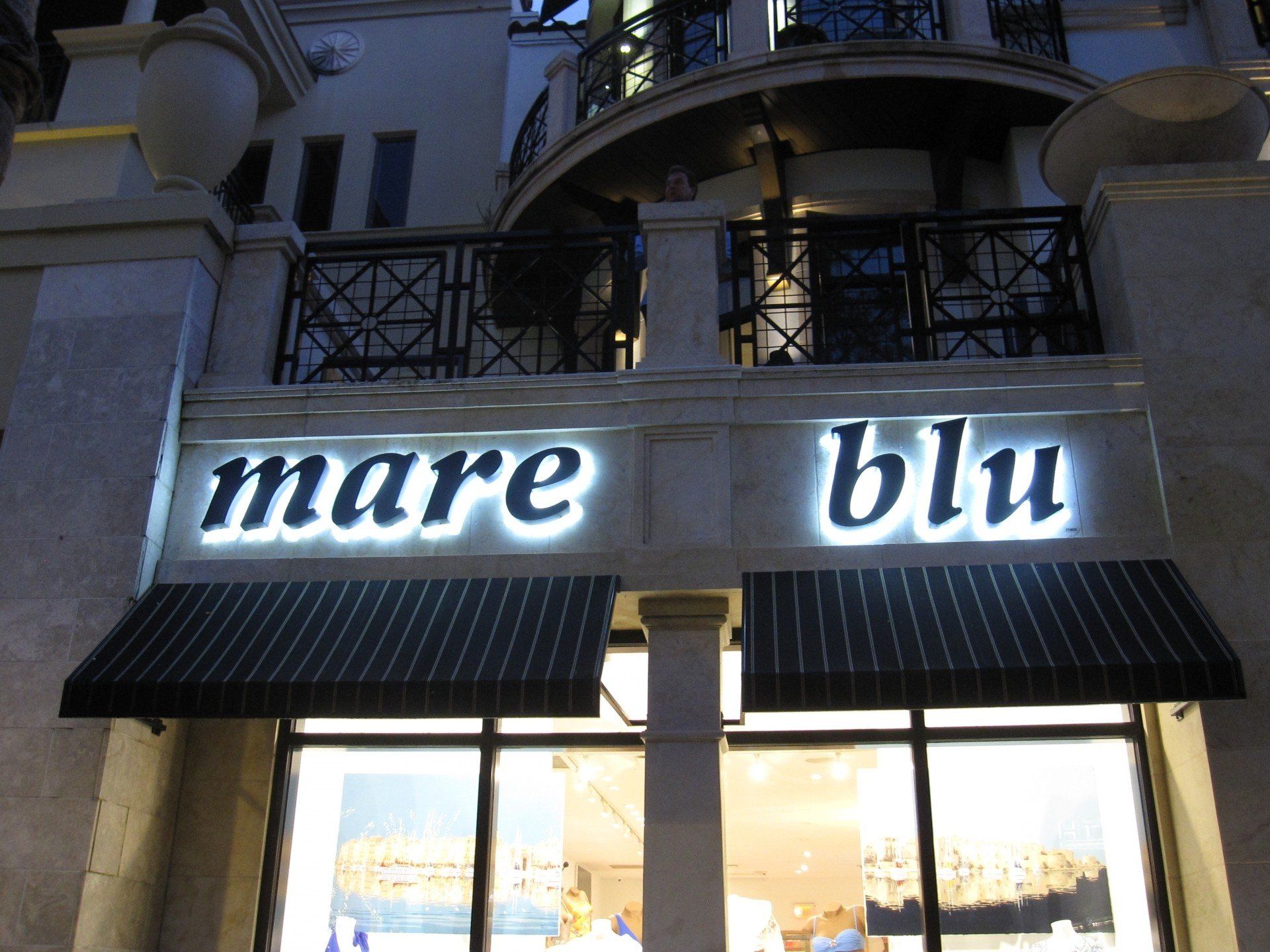 A store called mare blu is lit up at night