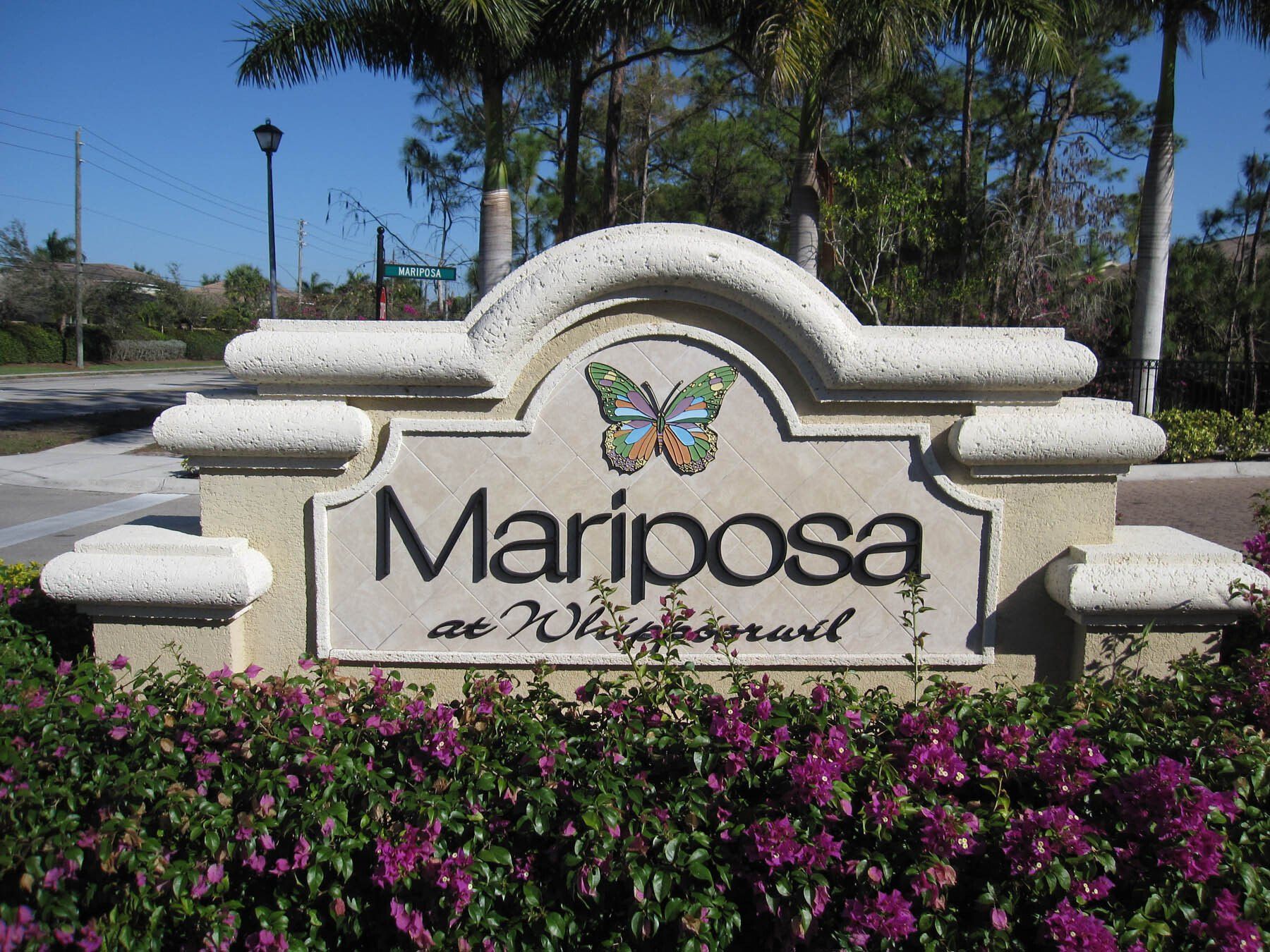 A sign for mariposa is surrounded by purple flowers