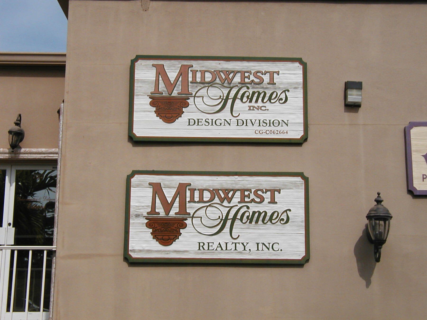 Two signs on the side of a building for midwest homes realty inc.
