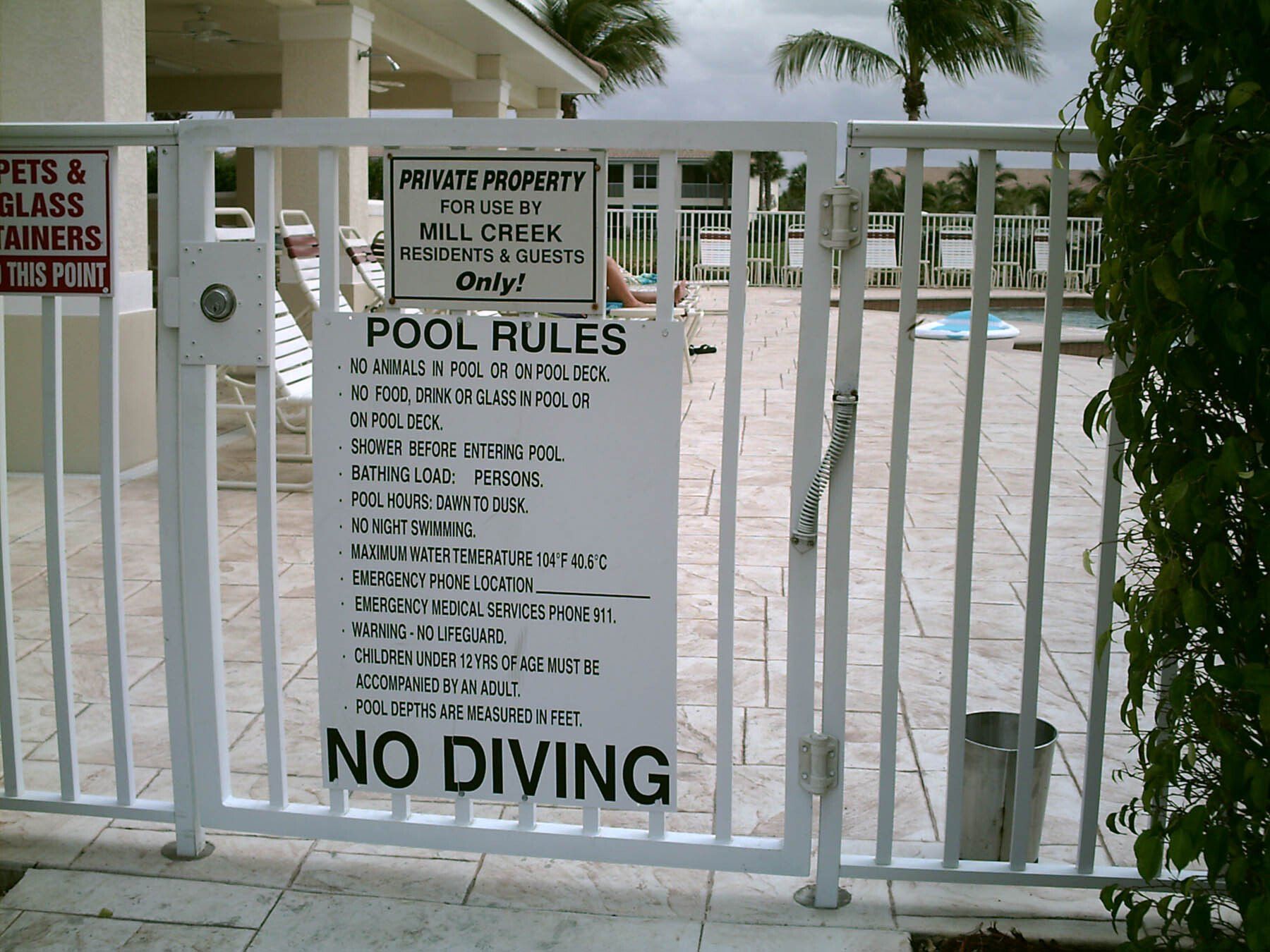 A fence with a sign that says pool rules and no diving