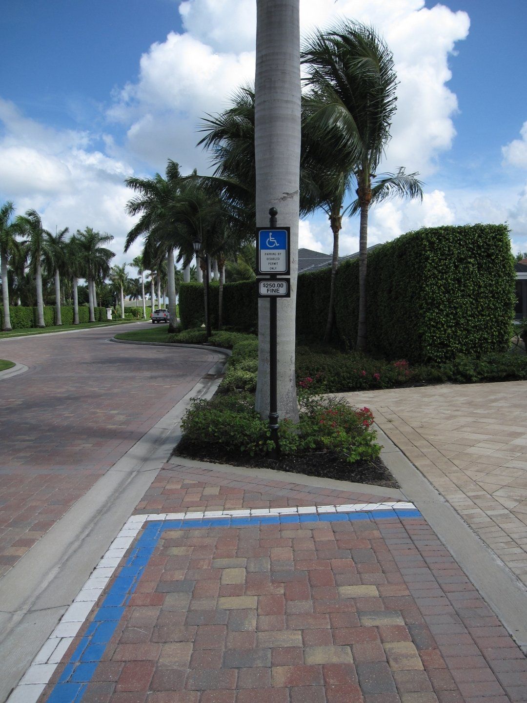 A brick sidewalk with a handicapped sign on a pole