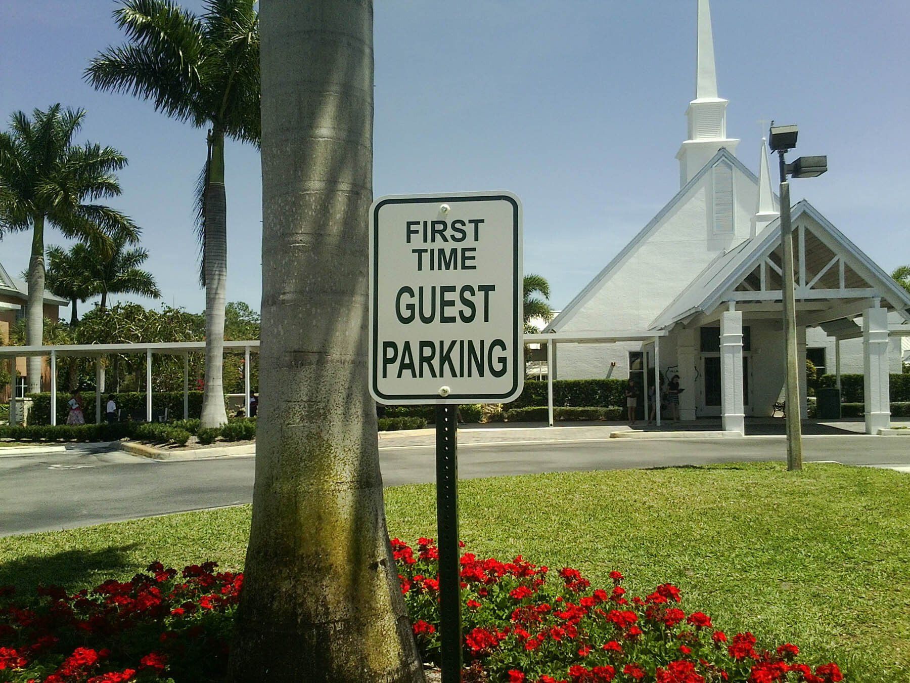 A sign that says first time guest parking in front of a church