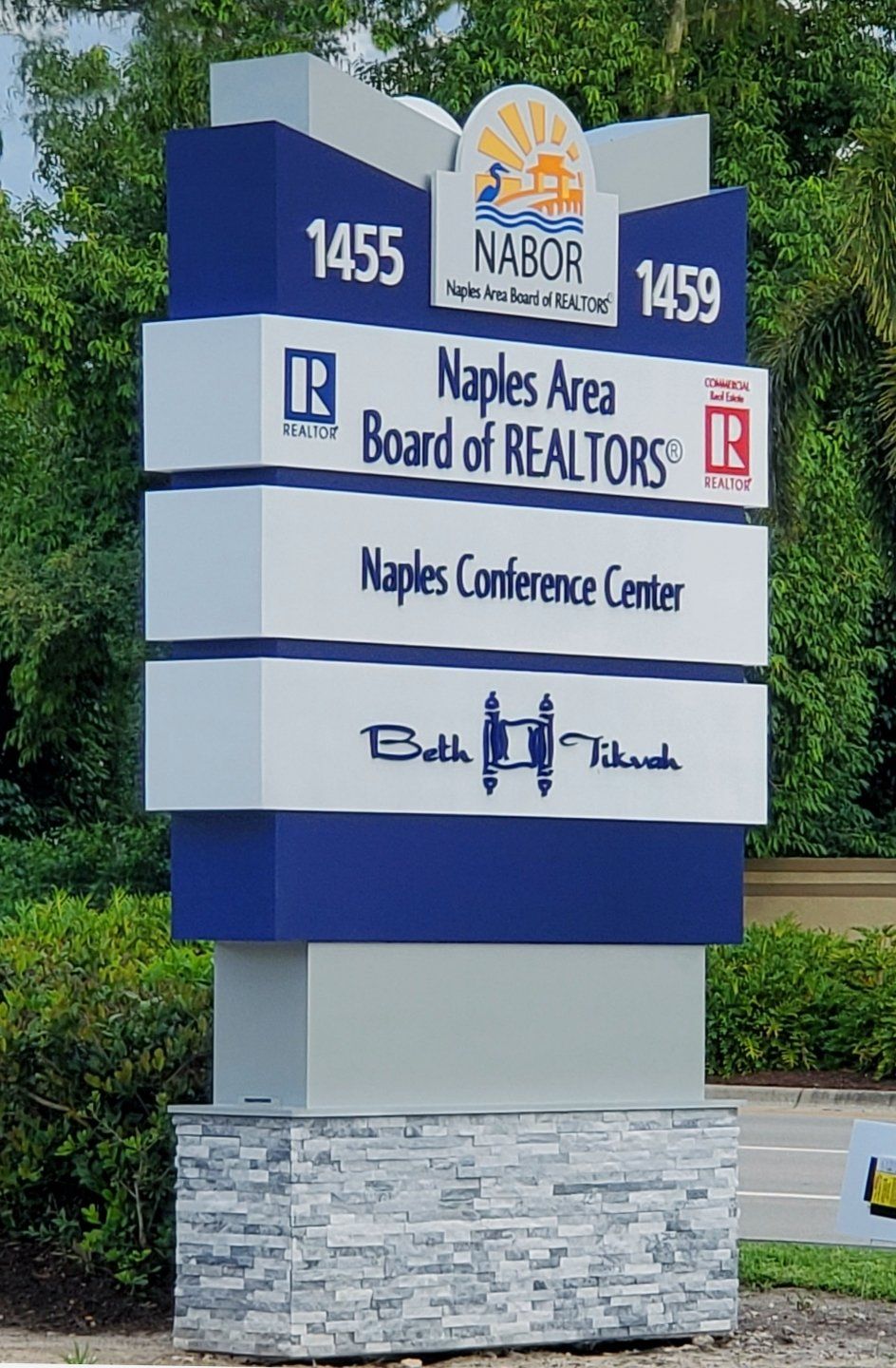 A blue and white sign for naples area board of realtors