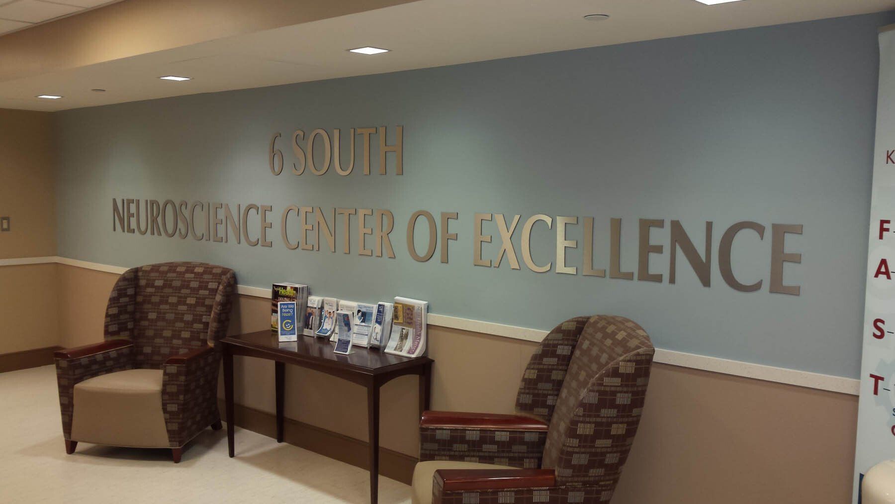 There are two chairs and a table in the lobby of the neuroscience center of excellence.