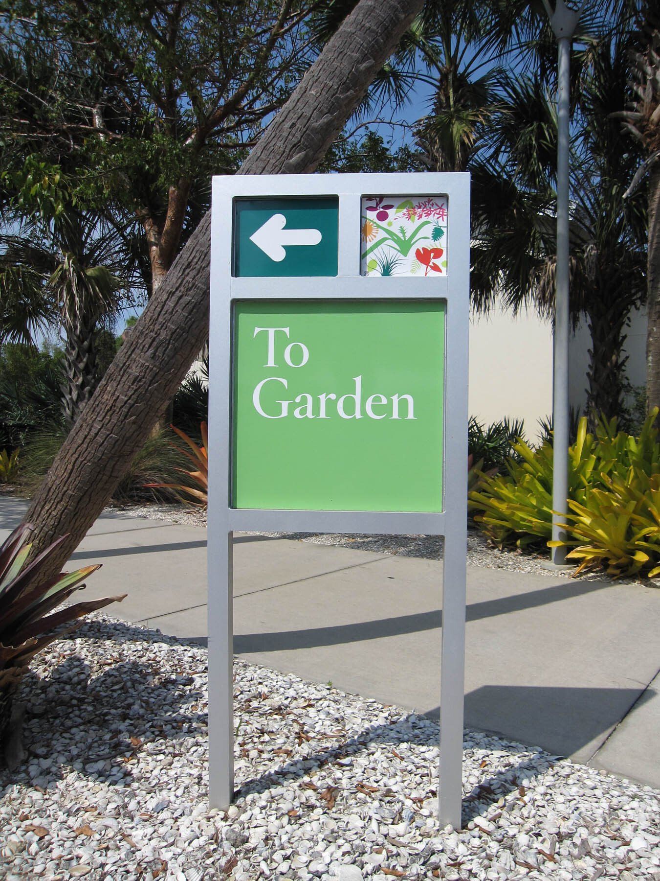 A green and silver sign that says to garden