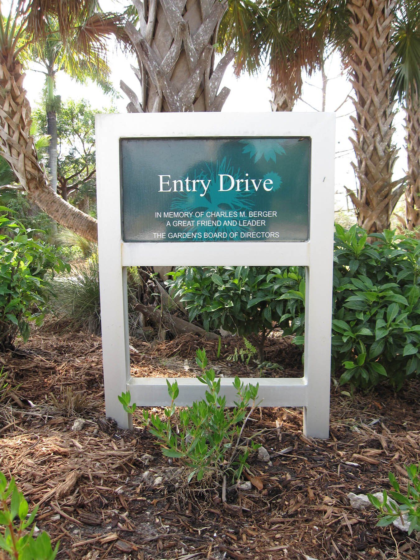 A sign that says entry drive is surrounded by trees and bushes