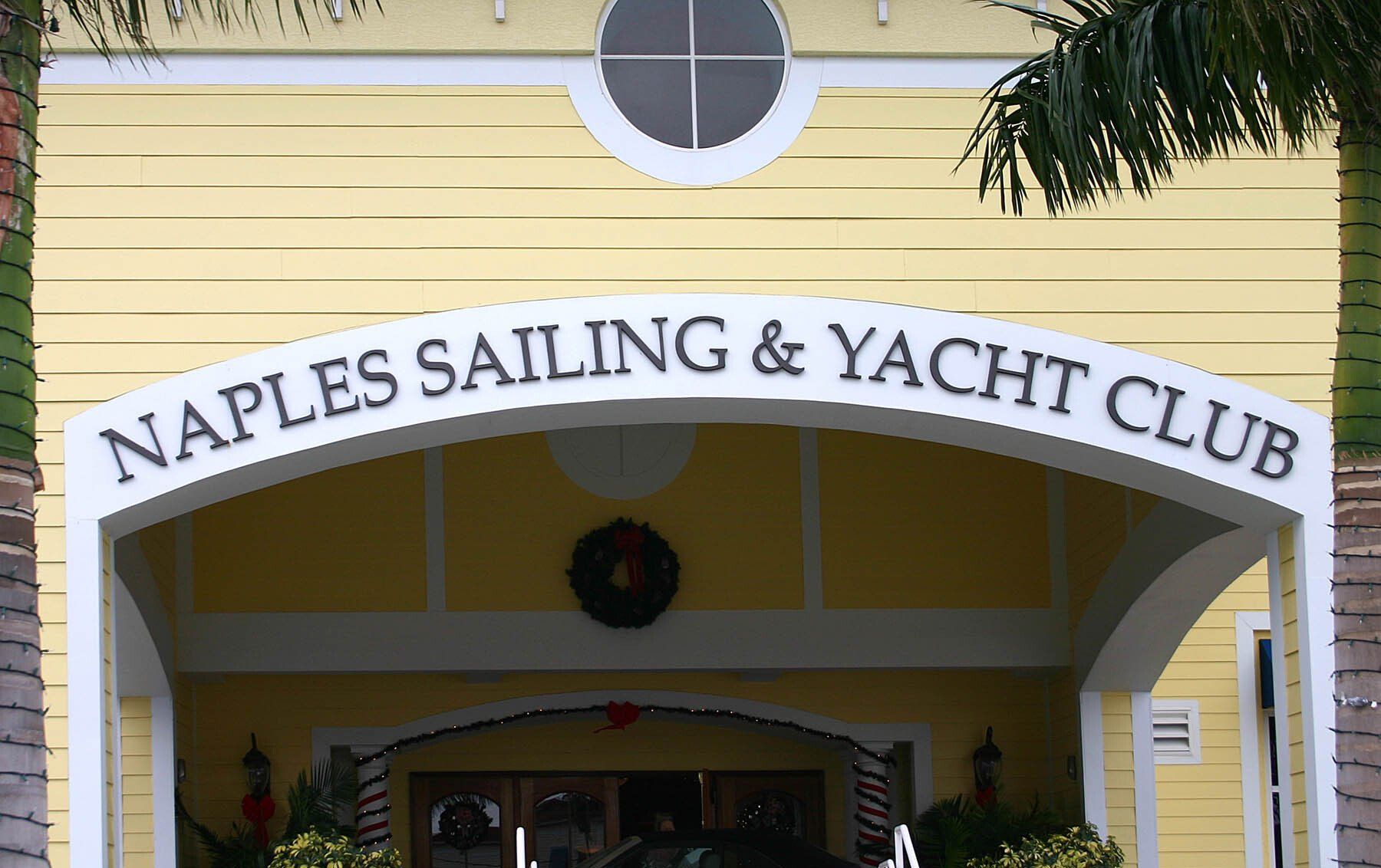 A yellow building with a sign that says naples sailing & yacht club