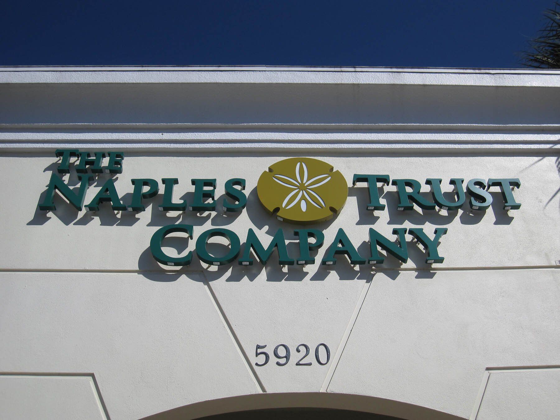 A naples trust company sign on a white building
