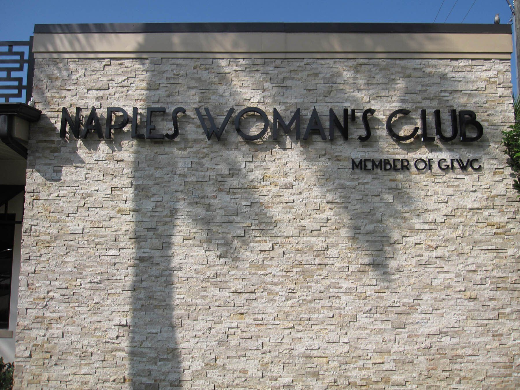 A sign for charles woman 's club on a brick wall