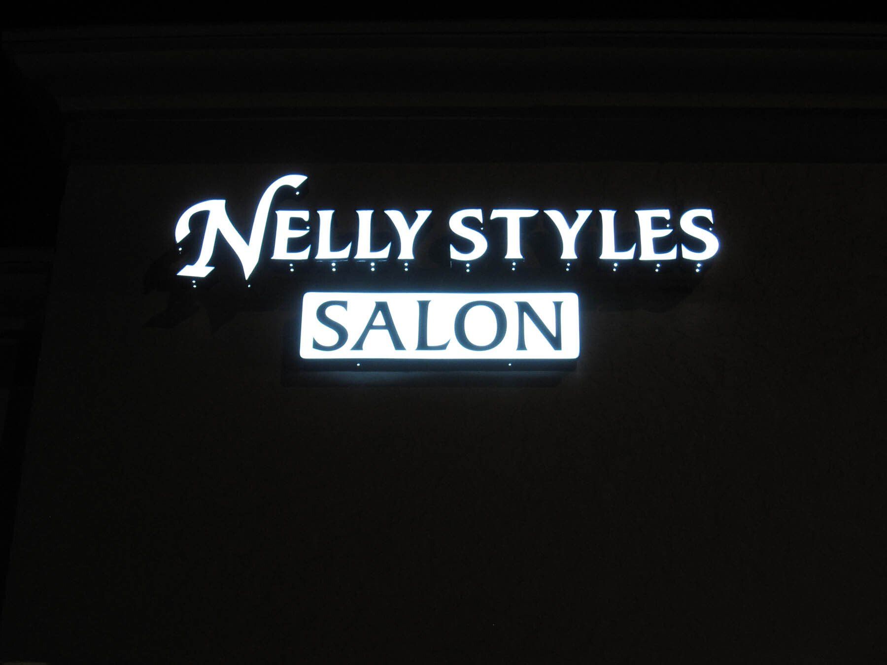 A neon sign for nelly styles salon is lit up