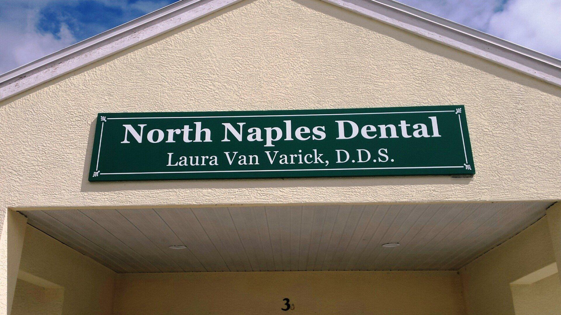 A green sign on the side of a building says north naples dental